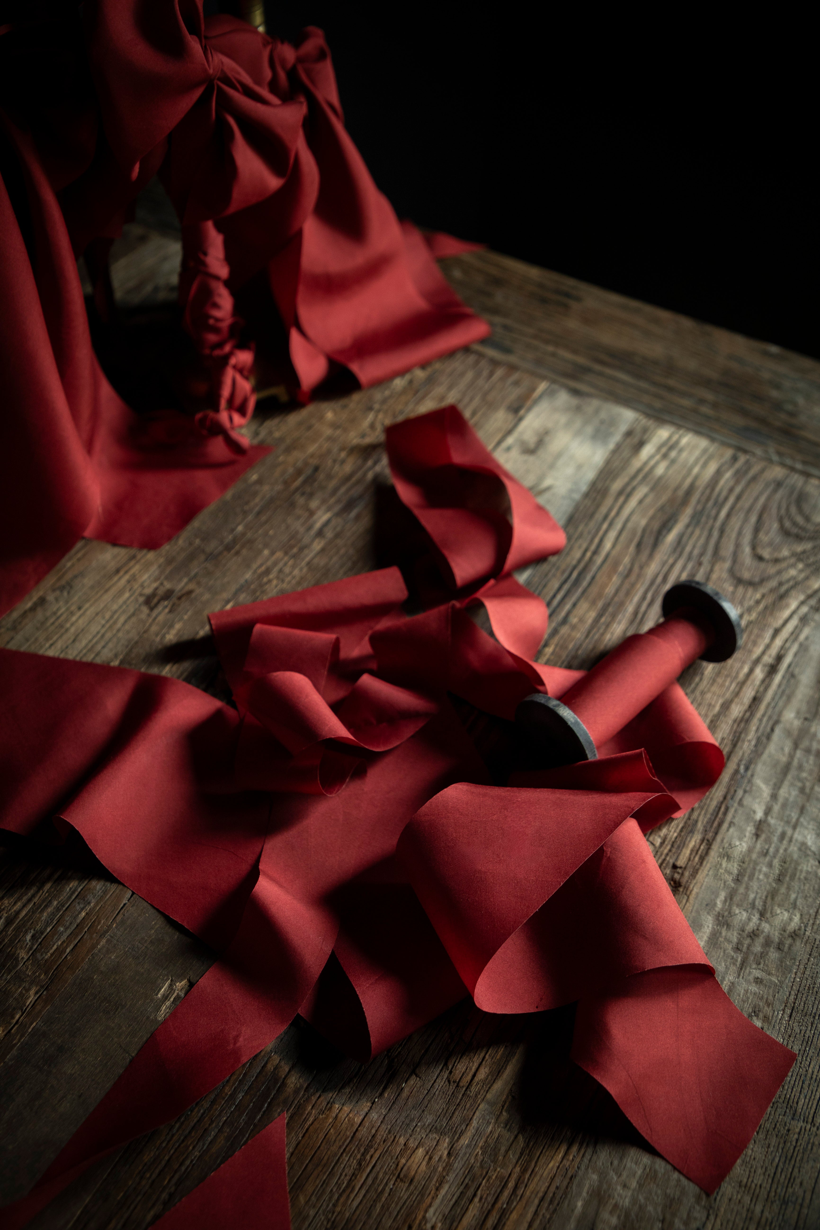 Red silk ribbon with a bow on a wooden surface