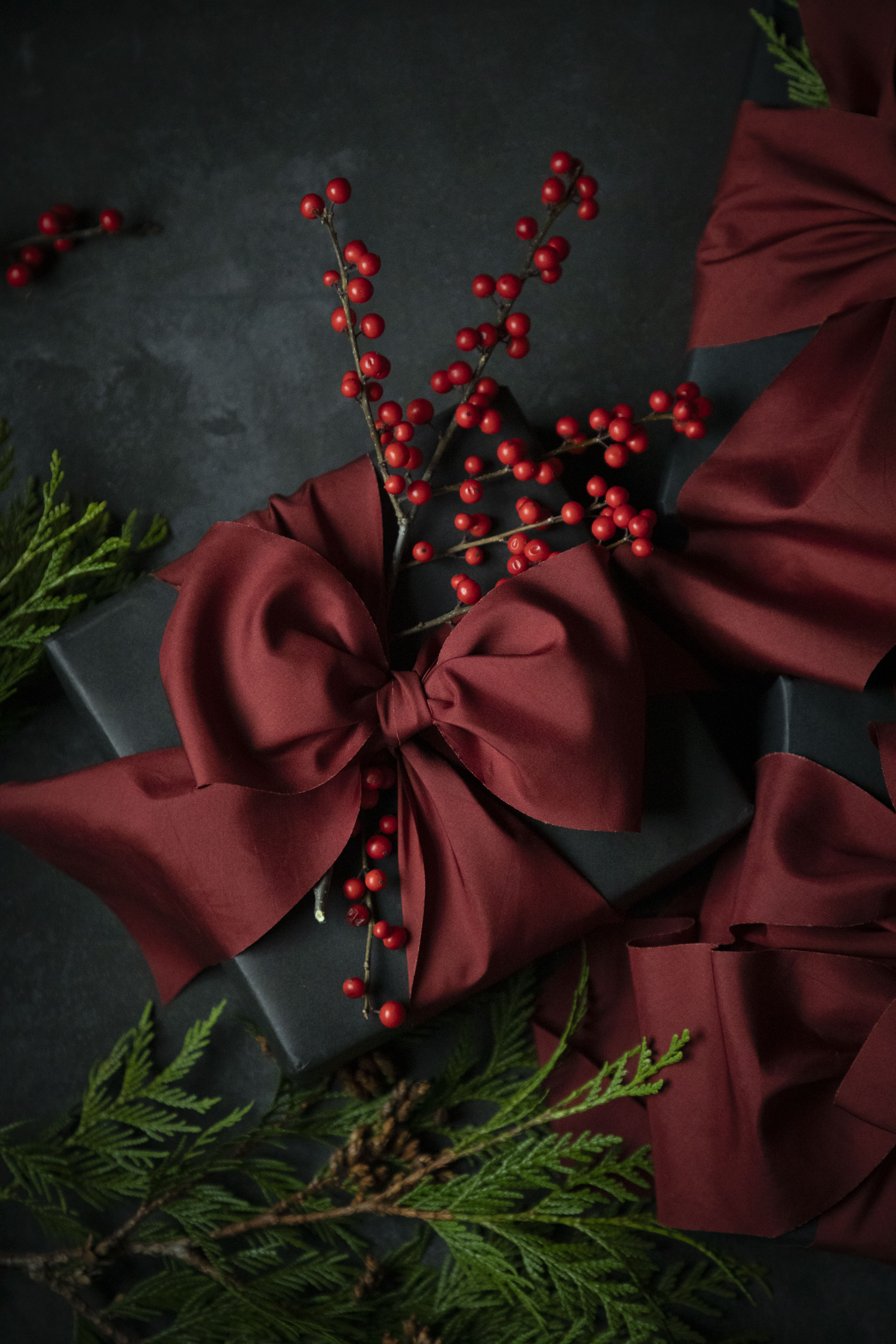 Black gift box with a red ribbon and berries on a dark background