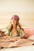 A model wearing a luxurious silk sleep mask adorned with delicate, nature-inspired botanical patterns. The mask exudes a fresh and restorative feel, combining elegance and comfort—a perfect addition to the Anthropologie aesthetic.