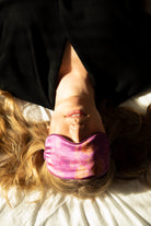 Person lying on their back with a purple eye mask on, wearing a black outfit.