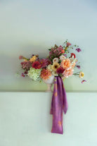 Floral arrangement with a purple ribbon on a white wall