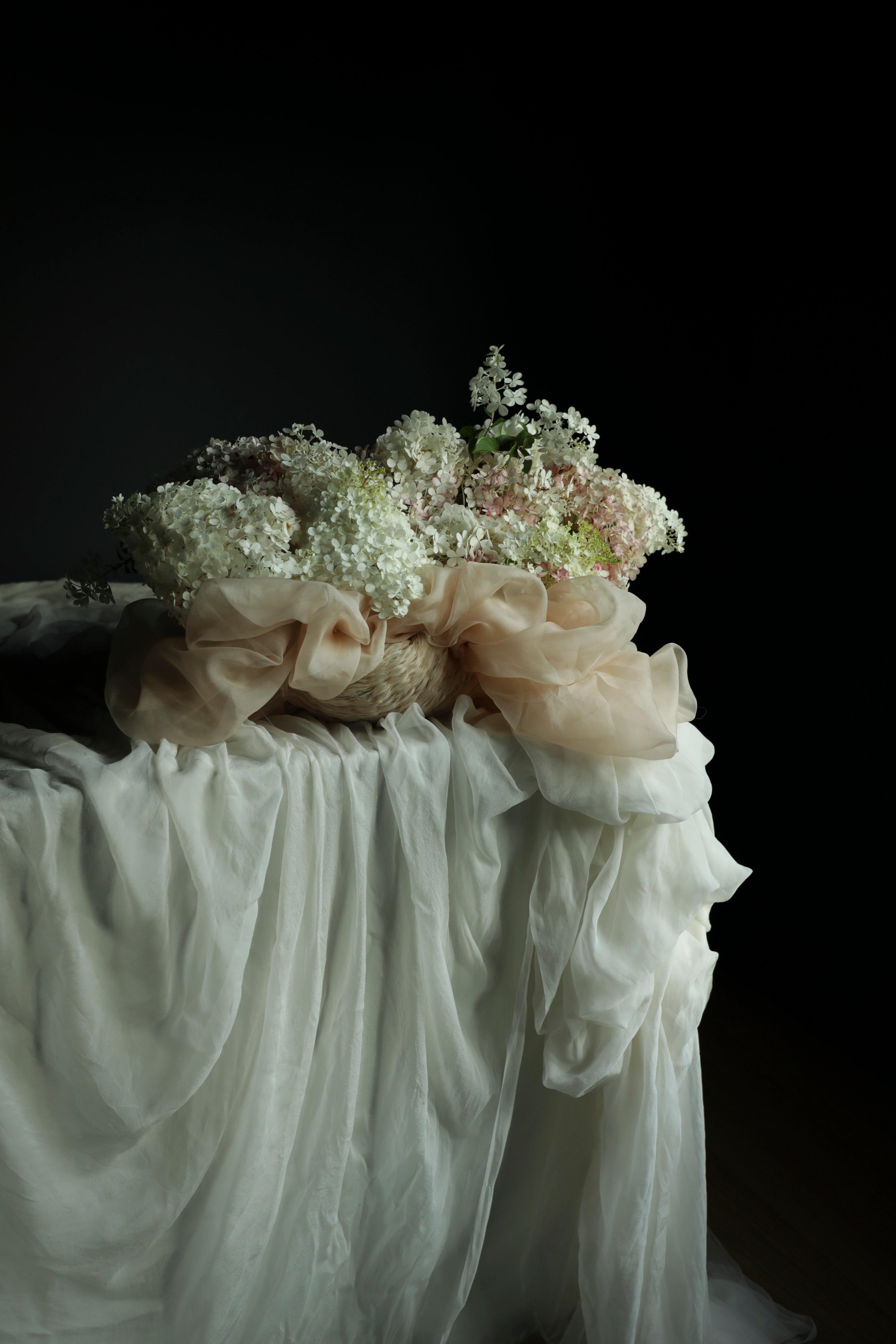 Floral arrangement on a draped surface with a dark background
