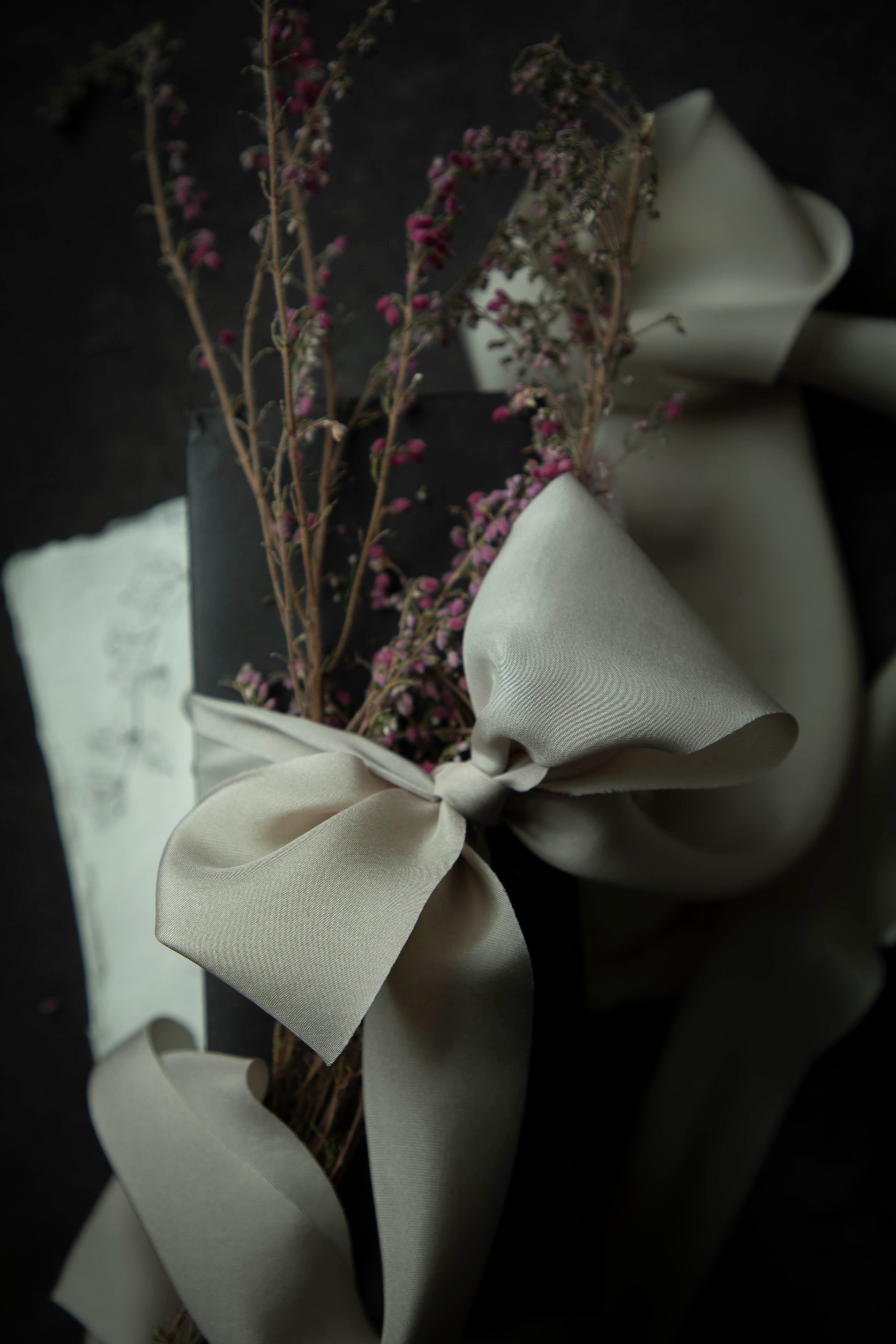 close up of champagne colored ribbon bow tied on a black box against a black background