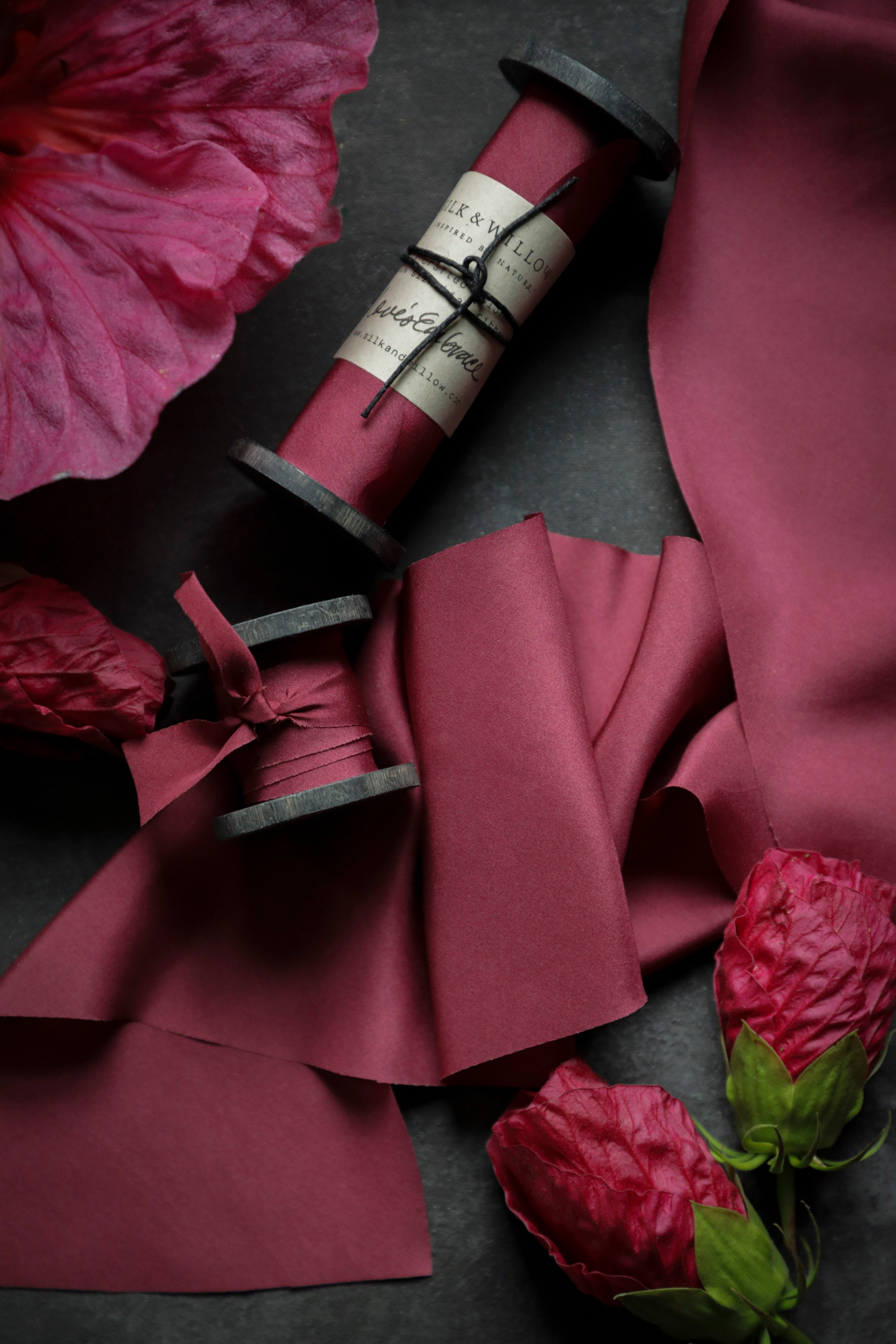red silk ribbon with pink flowers on a dark surface