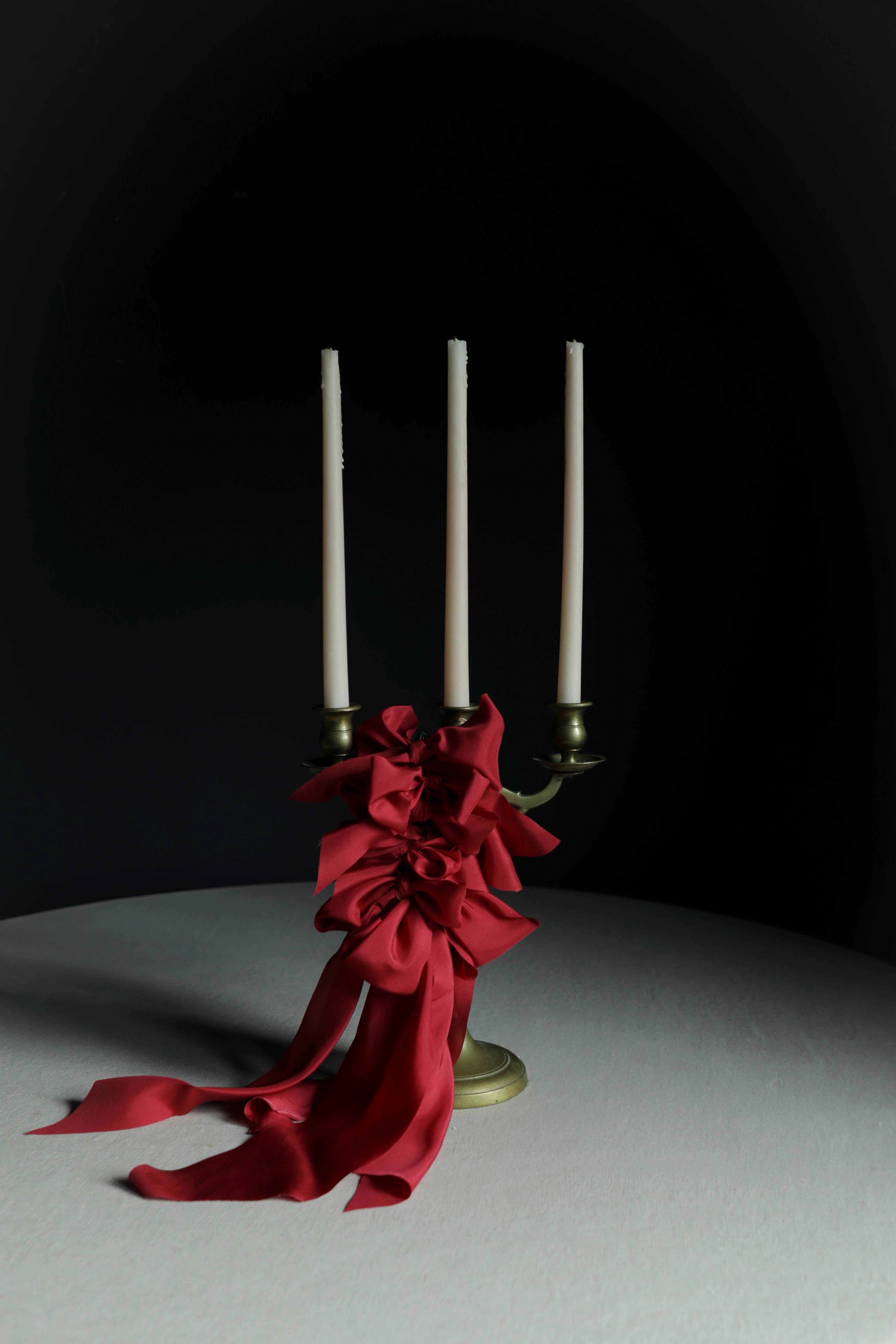 cherry red decor bows on candles against a black wall
