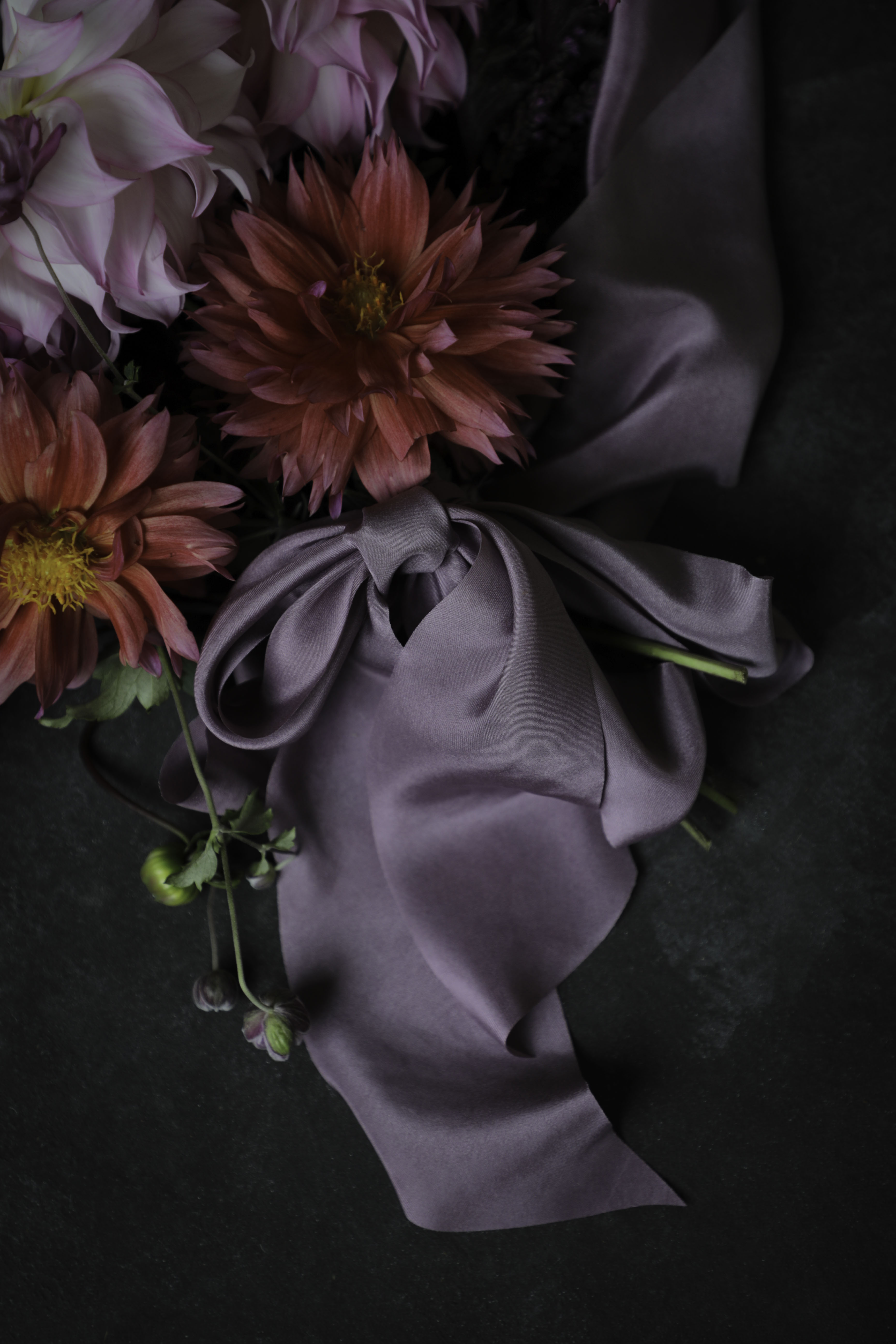 close up od a purple silk ribbon bow tied on the stems of a dahlia bouquet of flowers