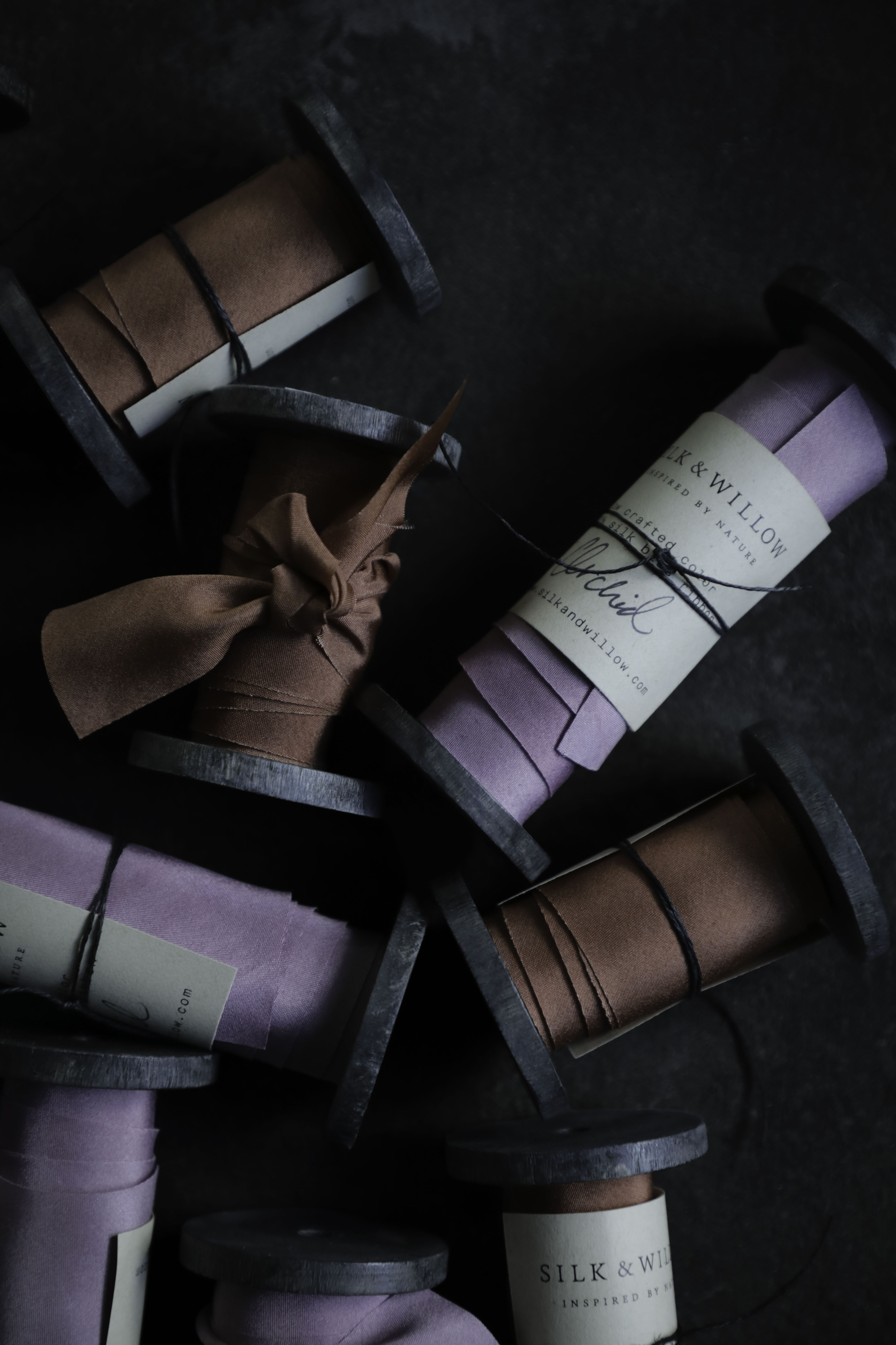 purple and rust colored hand dyed silk ribbons wound on wooden spools