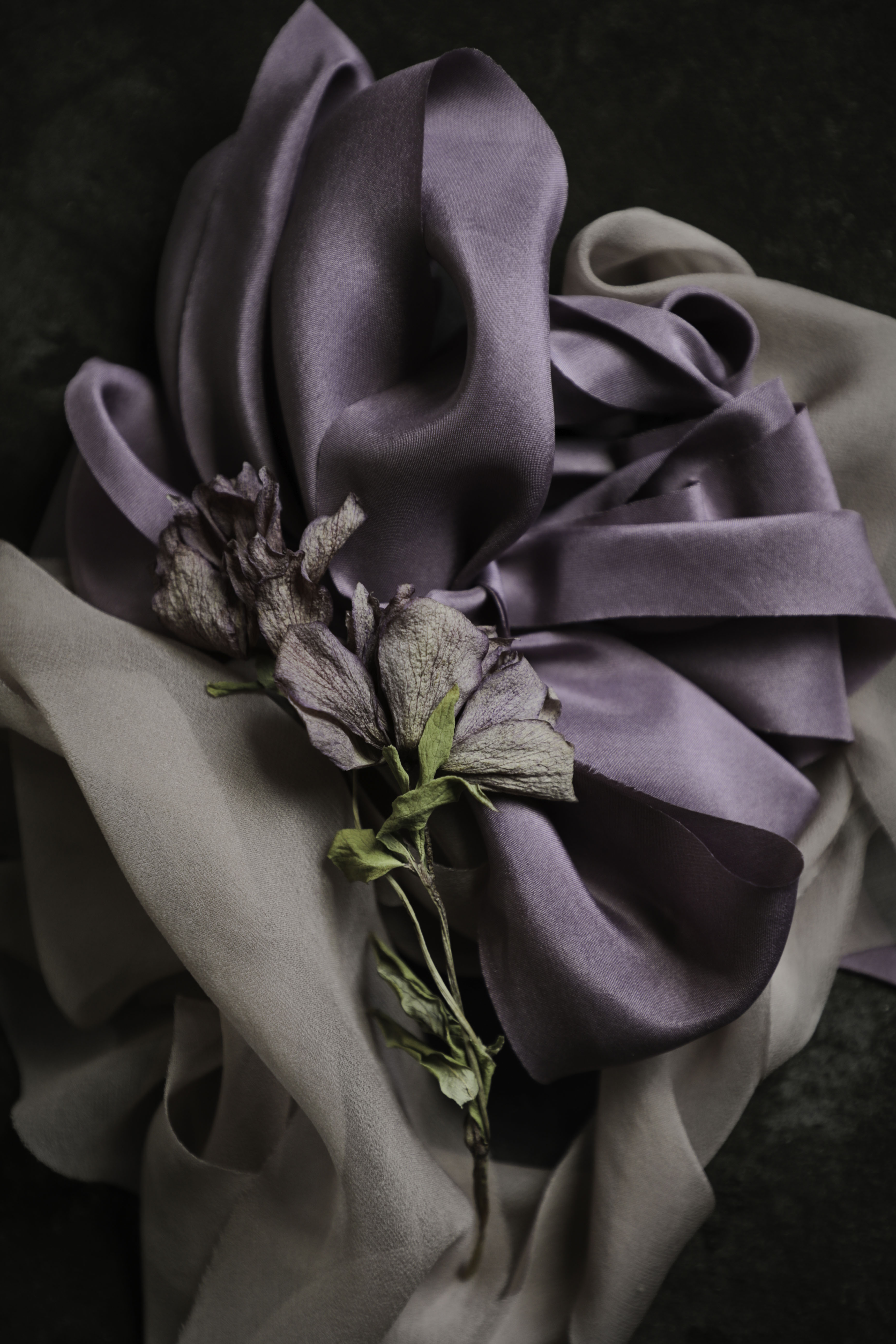 pile of purple and mauve silk ribbons with a dried flower with matching colors.