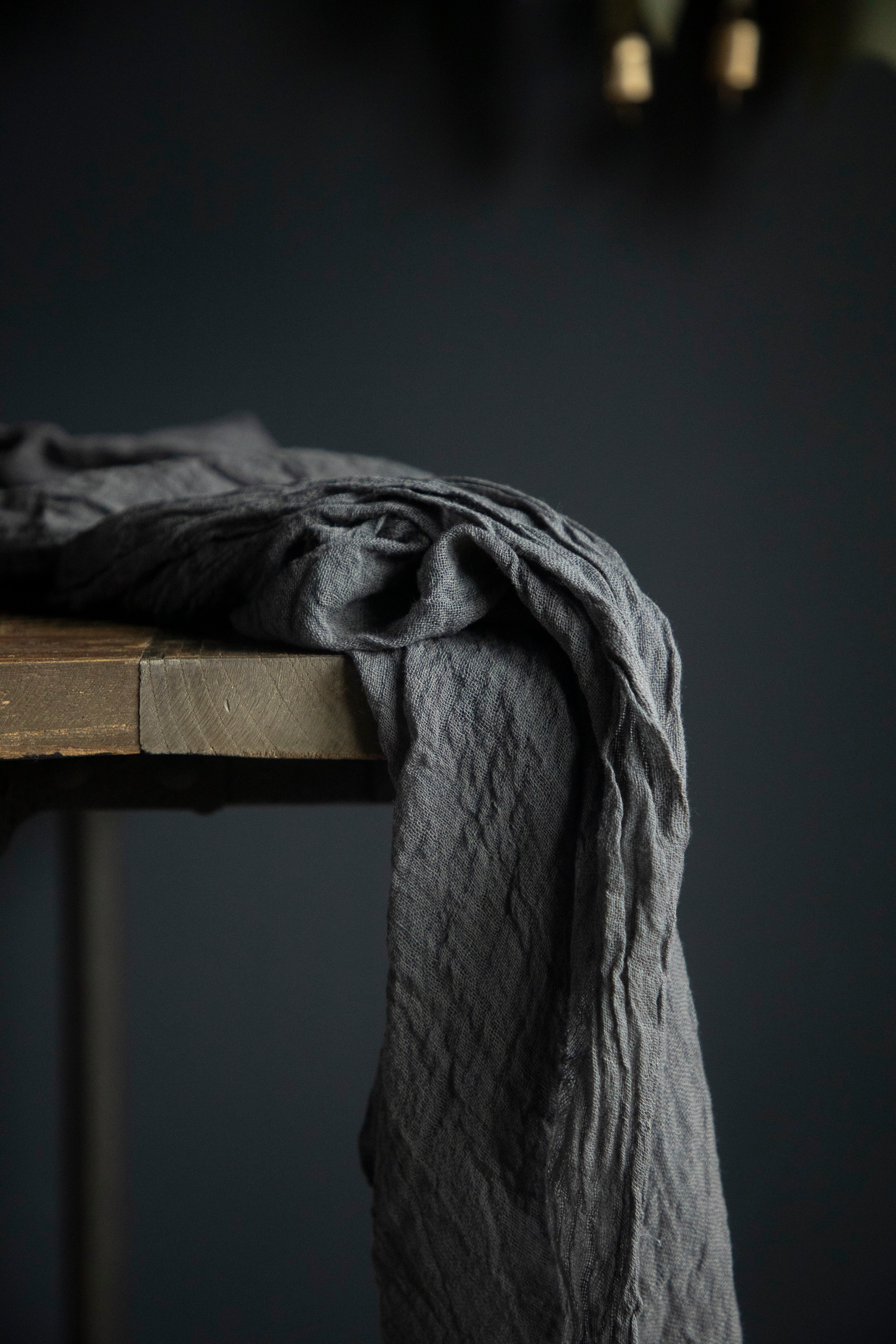 Dark gray fabric draped over a wooden surface against a dark background