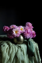 Pink flowers in a metallic vase on a green cloth with a dark background