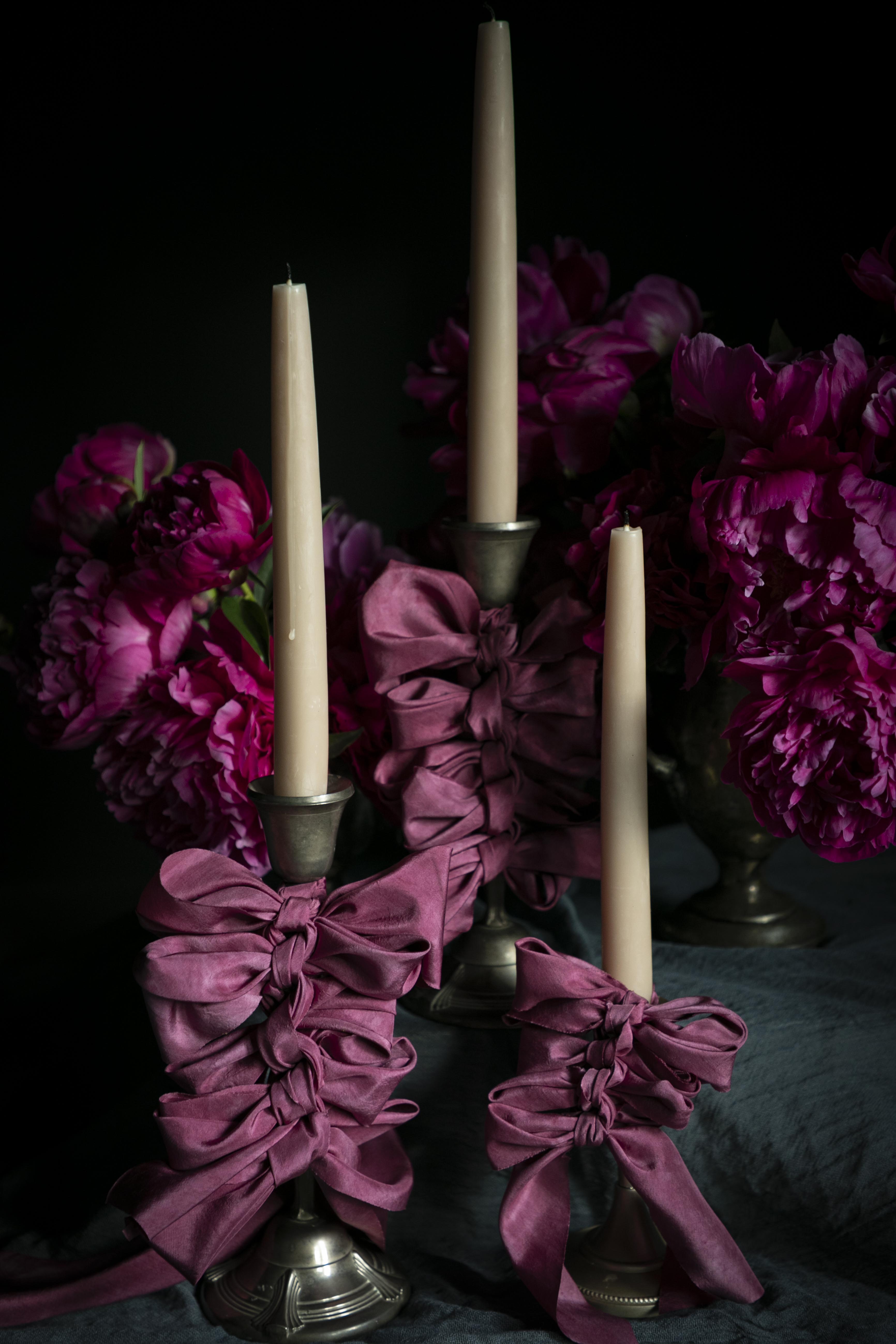 opalite aesthetic. Decorative candle holders with purple ribbons and candles against a dark background