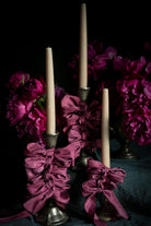 opalite aesthetic. Decorative candle holders with purple ribbons and candles against a dark background