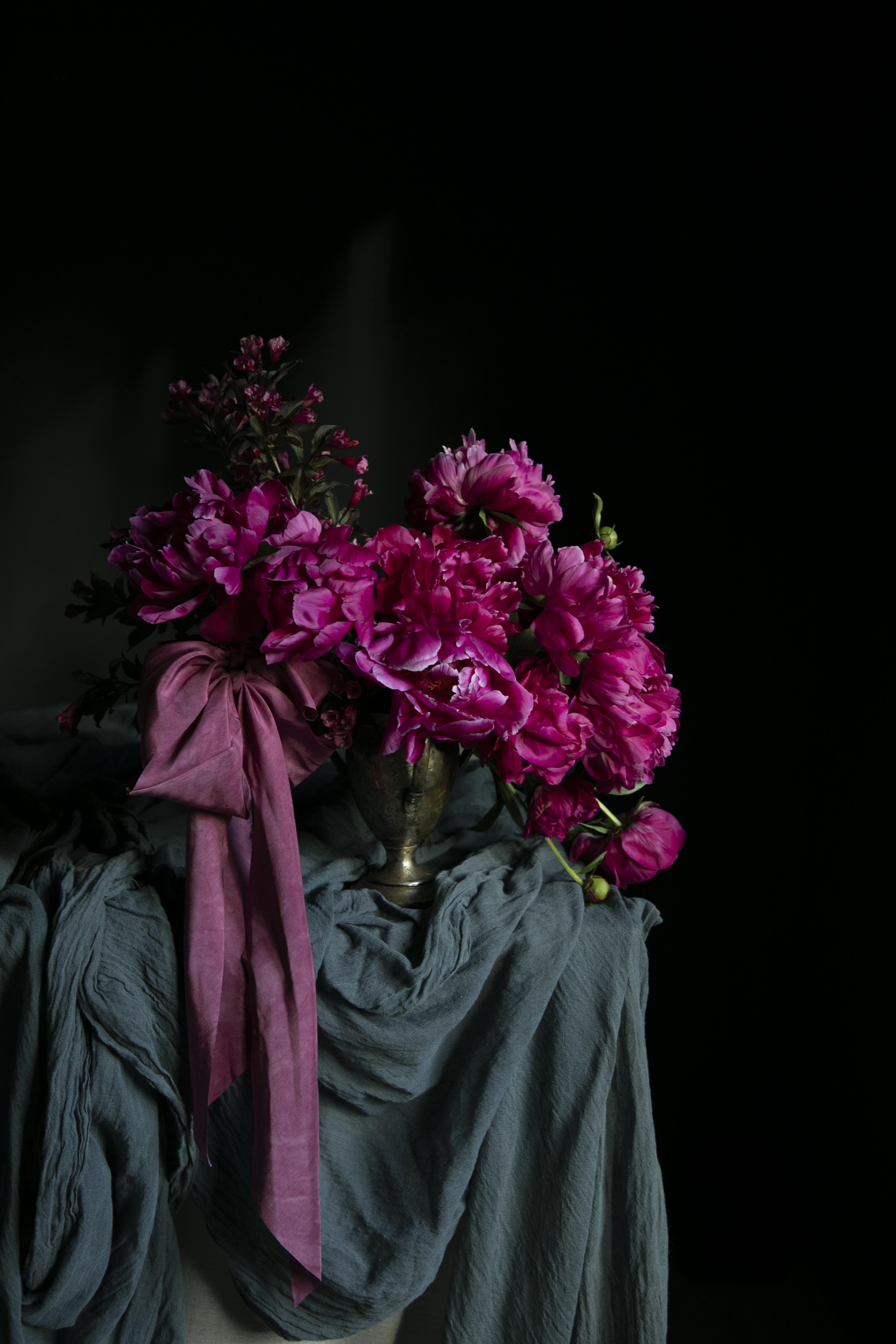 Bouquet of pink flowers with a pink ribbon on a dark background. Unique wedding trends 2027.