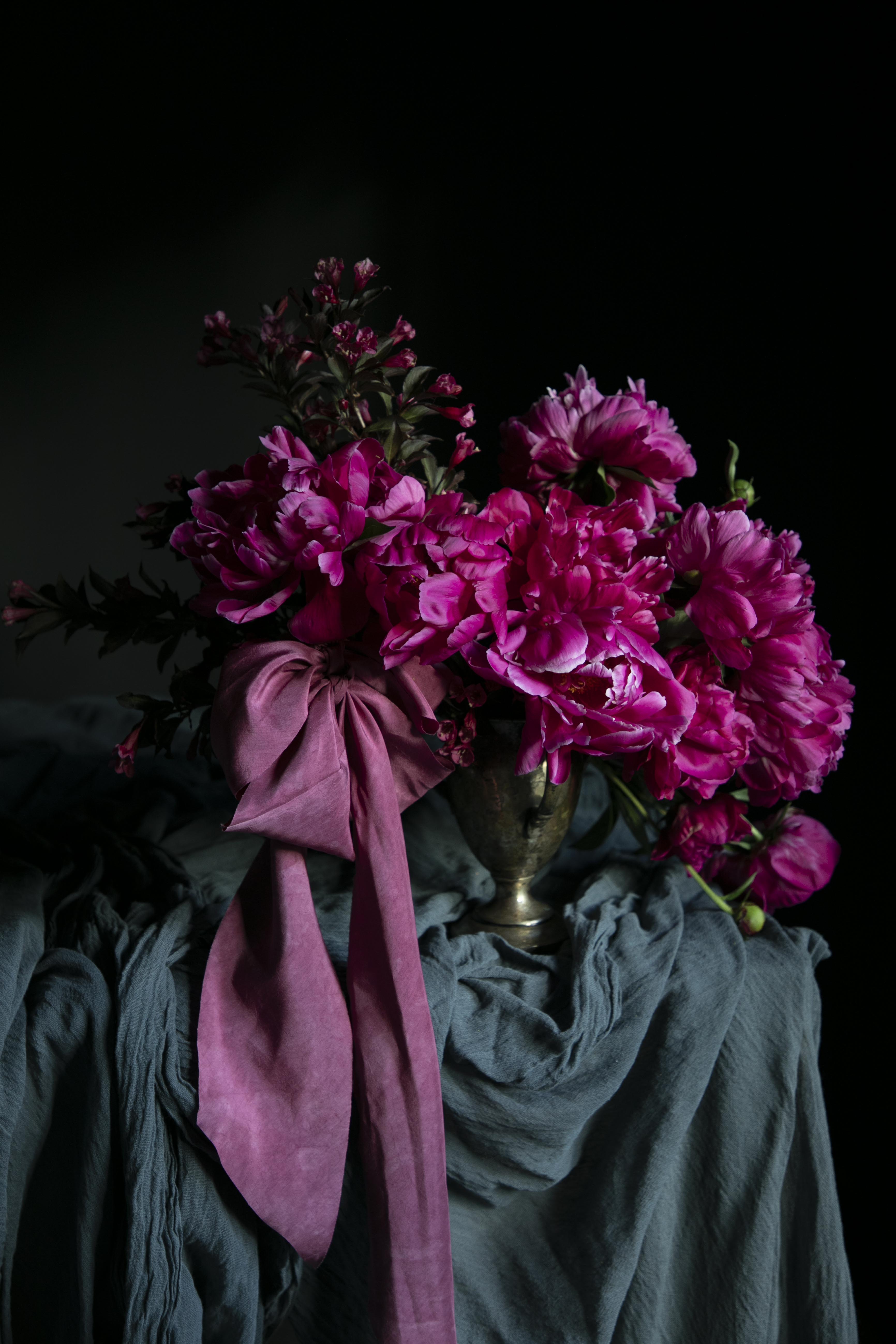 Bouquet of pink flowers with a purple ribbon on a dark background