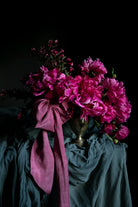 Bouquet of pink flowers with a purple ribbon on a dark background