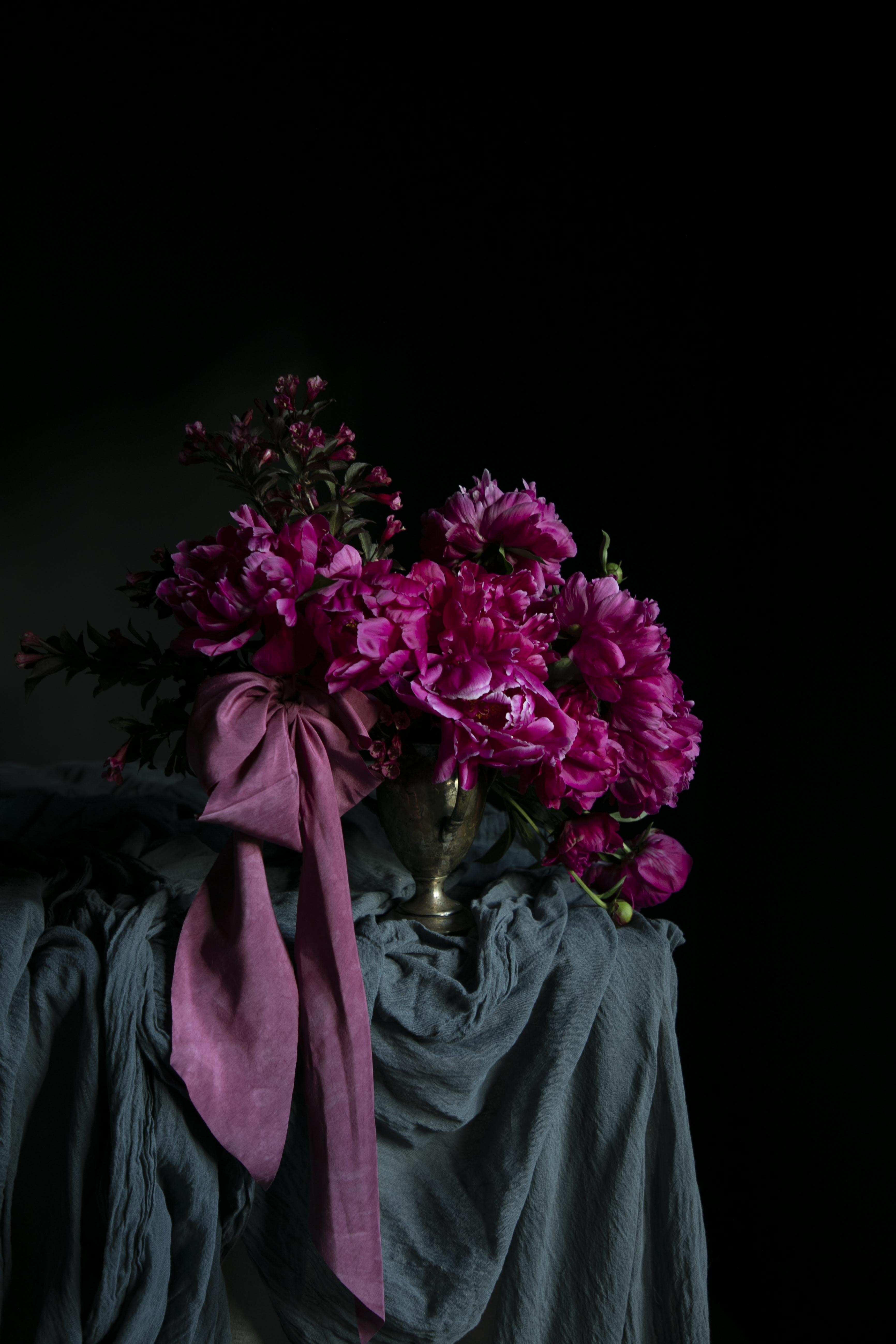Bouquet of pink flowers with a purple ribbon on a dark background