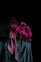 Bouquet of pink flowers with a purple ribbon on a dark background