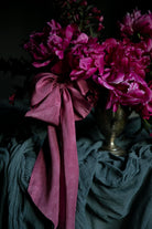 Pink flowers with a large pink bow in a silver vase on a dark background. opalite aesthetic.