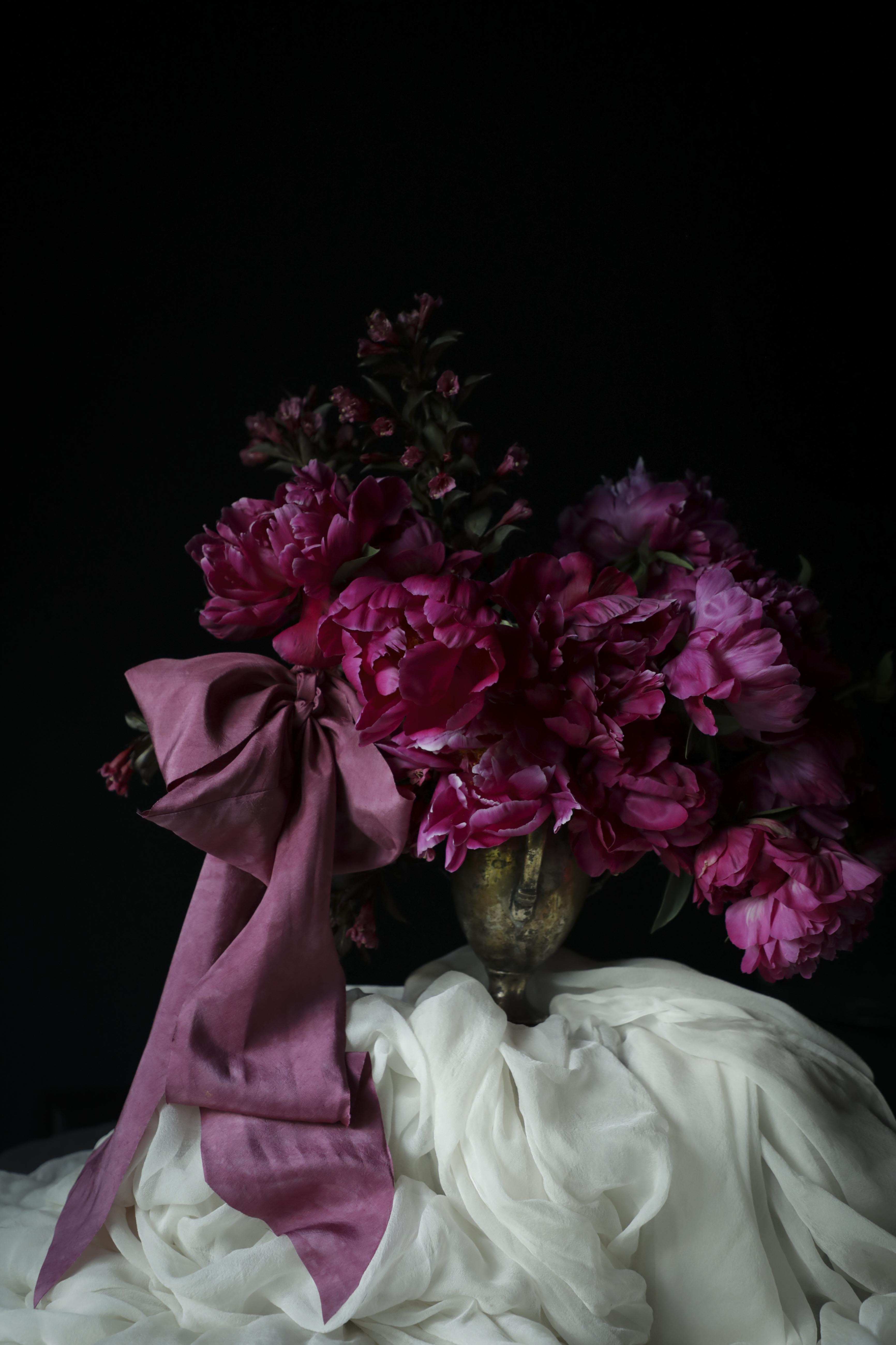 Bouquet of pink flowers with a purple ribbon on a dark background