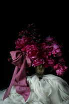 Bouquet of pink flowers with a purple ribbon on a dark background