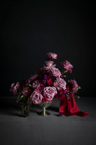 Bouquet of flowers with a red silk ribbon on a dark background