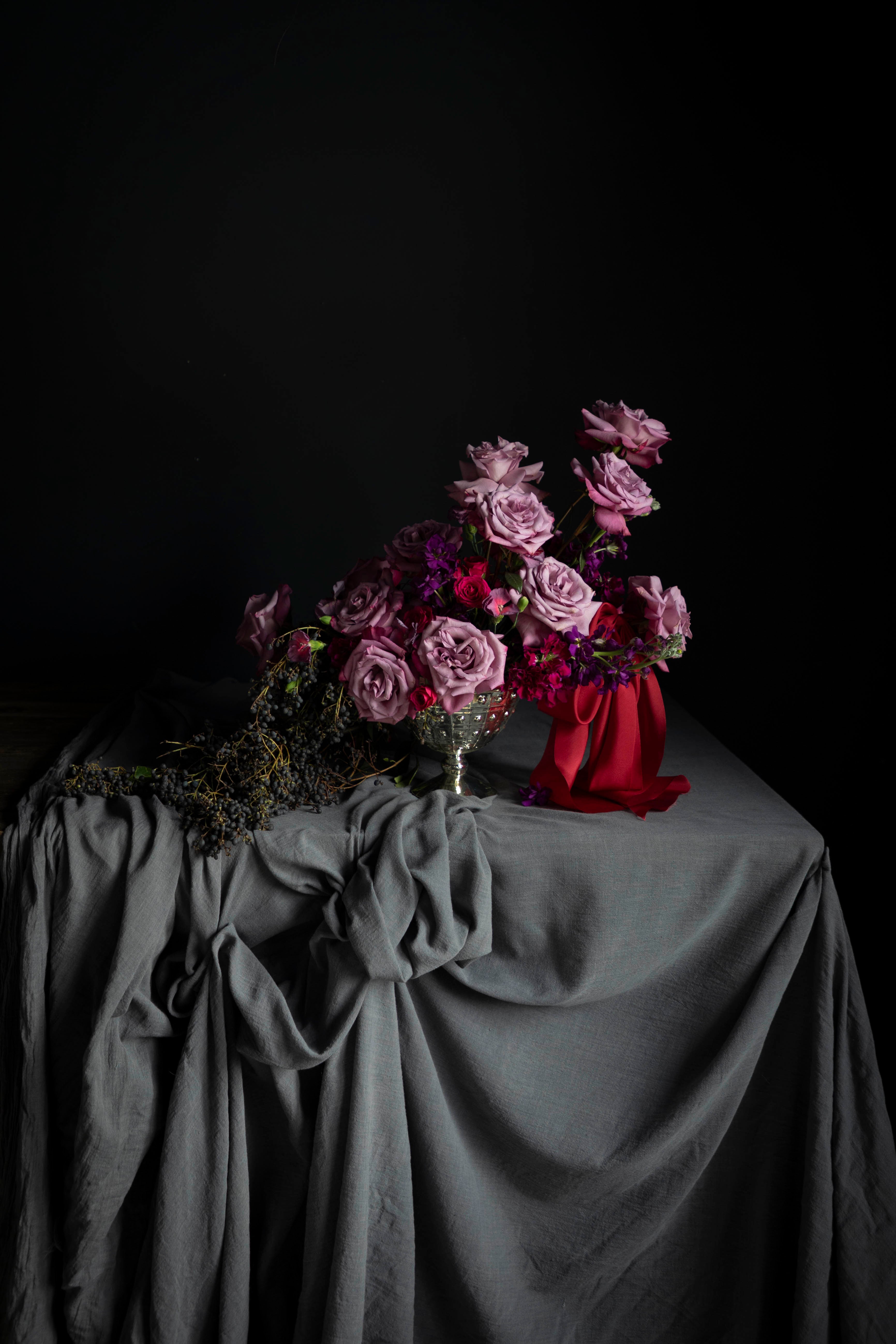 Bouquet of pink flowers on a draped table with a dark background