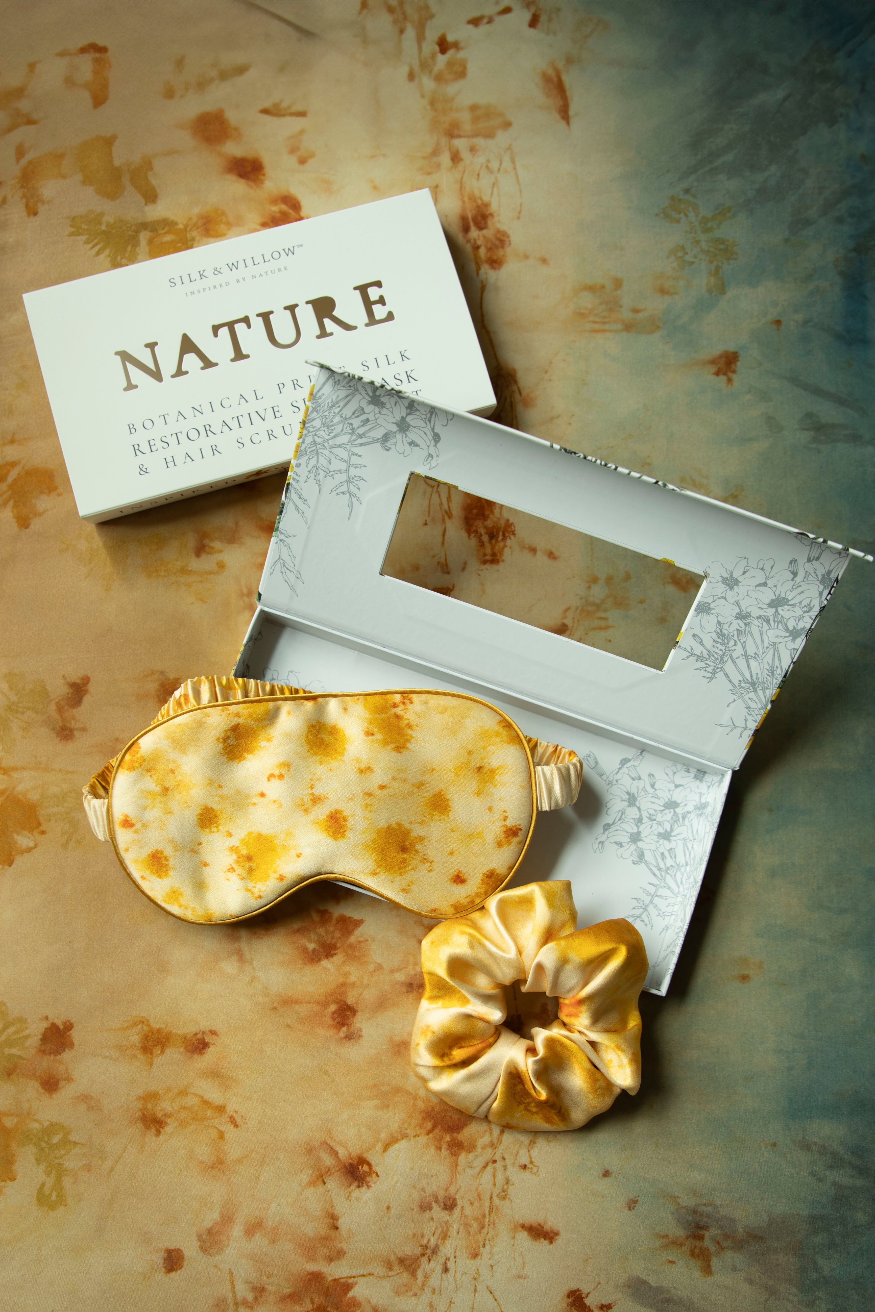 Gold-patterned eye mask and flower on a textured surface with 'NATURE' branding.