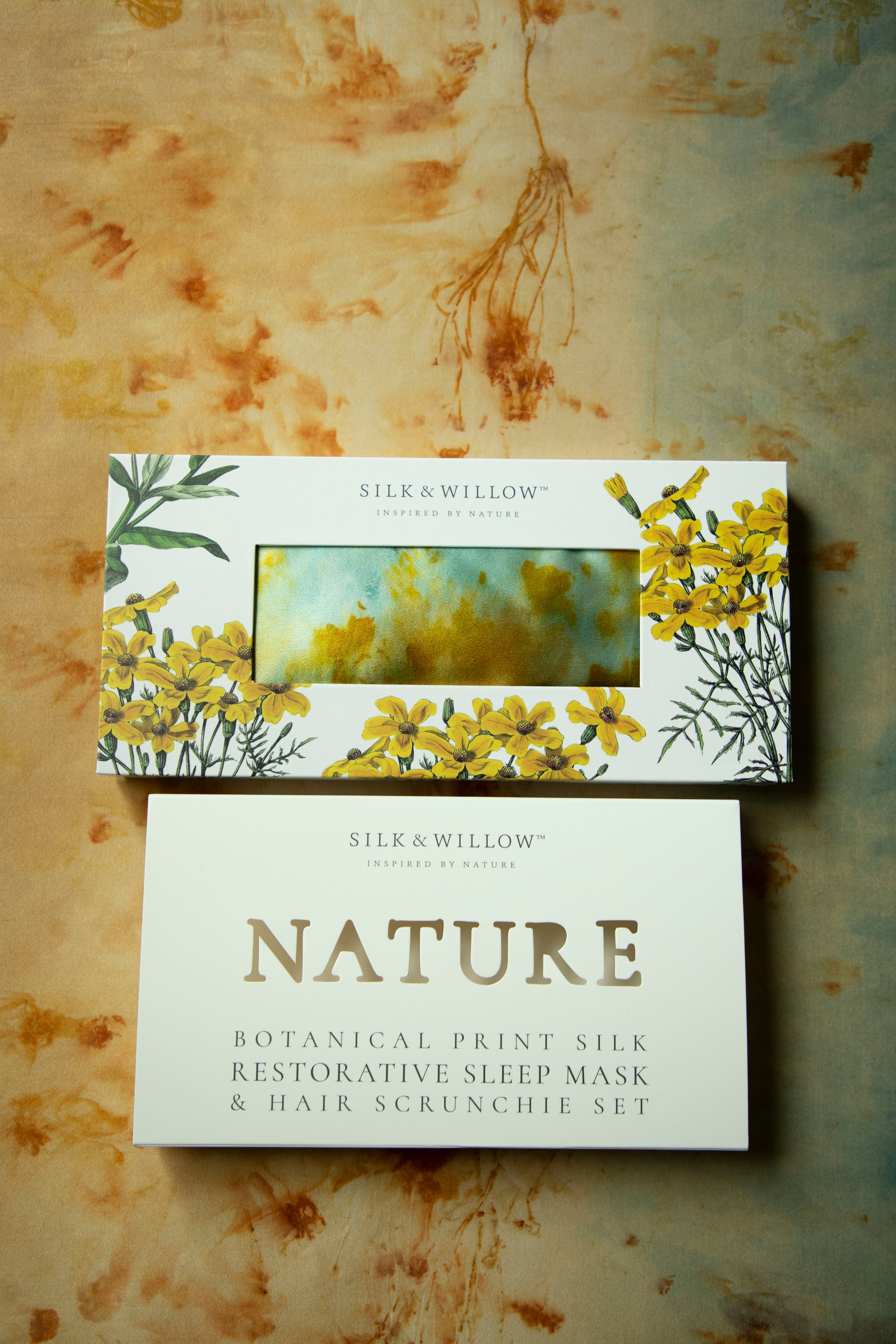 Silk and Willow botanical print silk restorative sleep mask and hair scrunchie set on a textured background