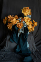 Bouquet of coral rose flowers wrapped with blue silk ribbon bows against a dark background