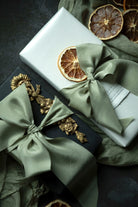 Gifts wrapped in green ribbons with dried oranges on a dark surface