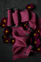 Purple ribbons on spools with purple flowers on a dark background