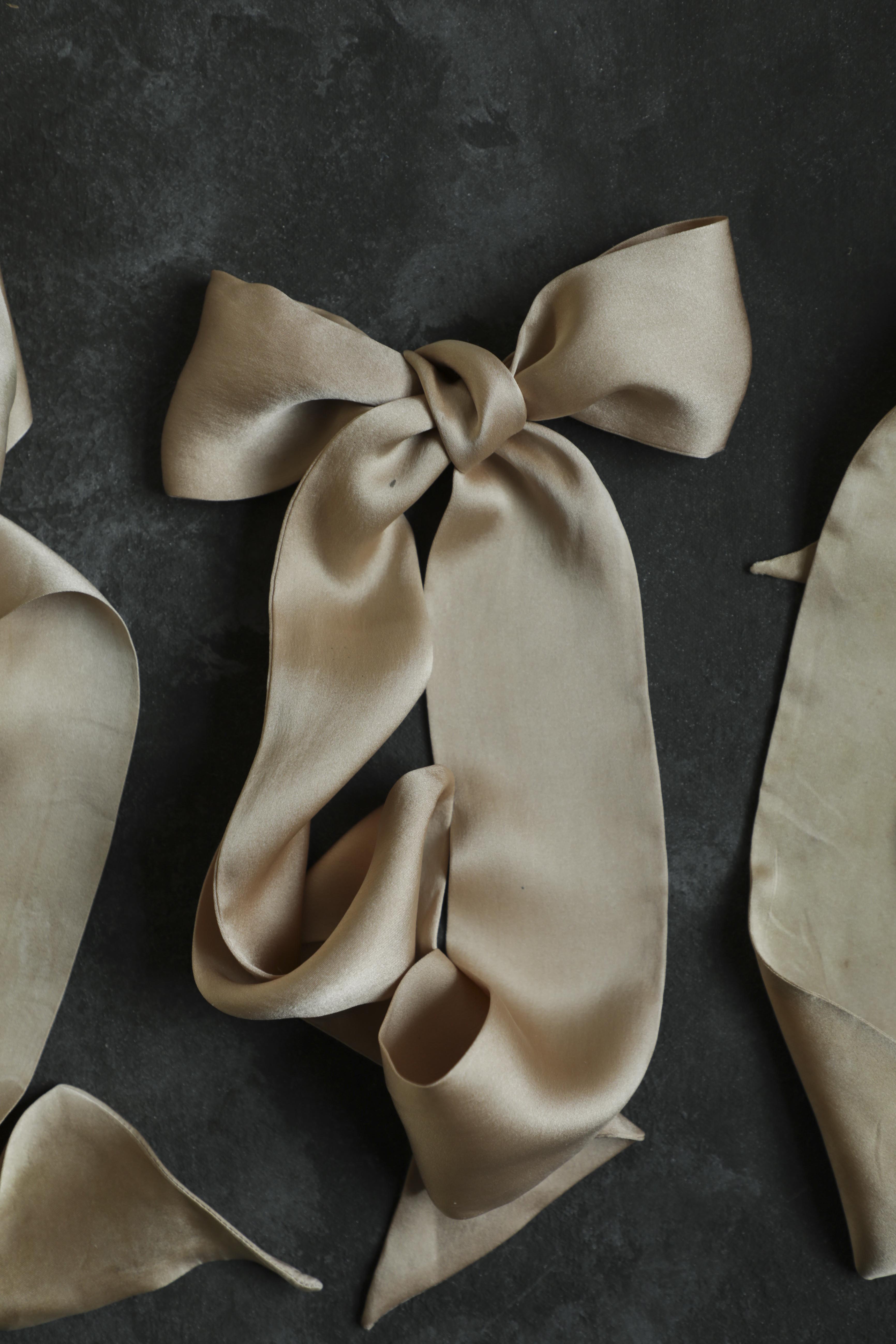 Beige silk scarf tied in a bow on a dark background