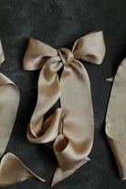 Beige silk scarf tied in a bow on a dark background