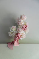 Decorative floral arrangement with peonies and pink ribbons on a plain background