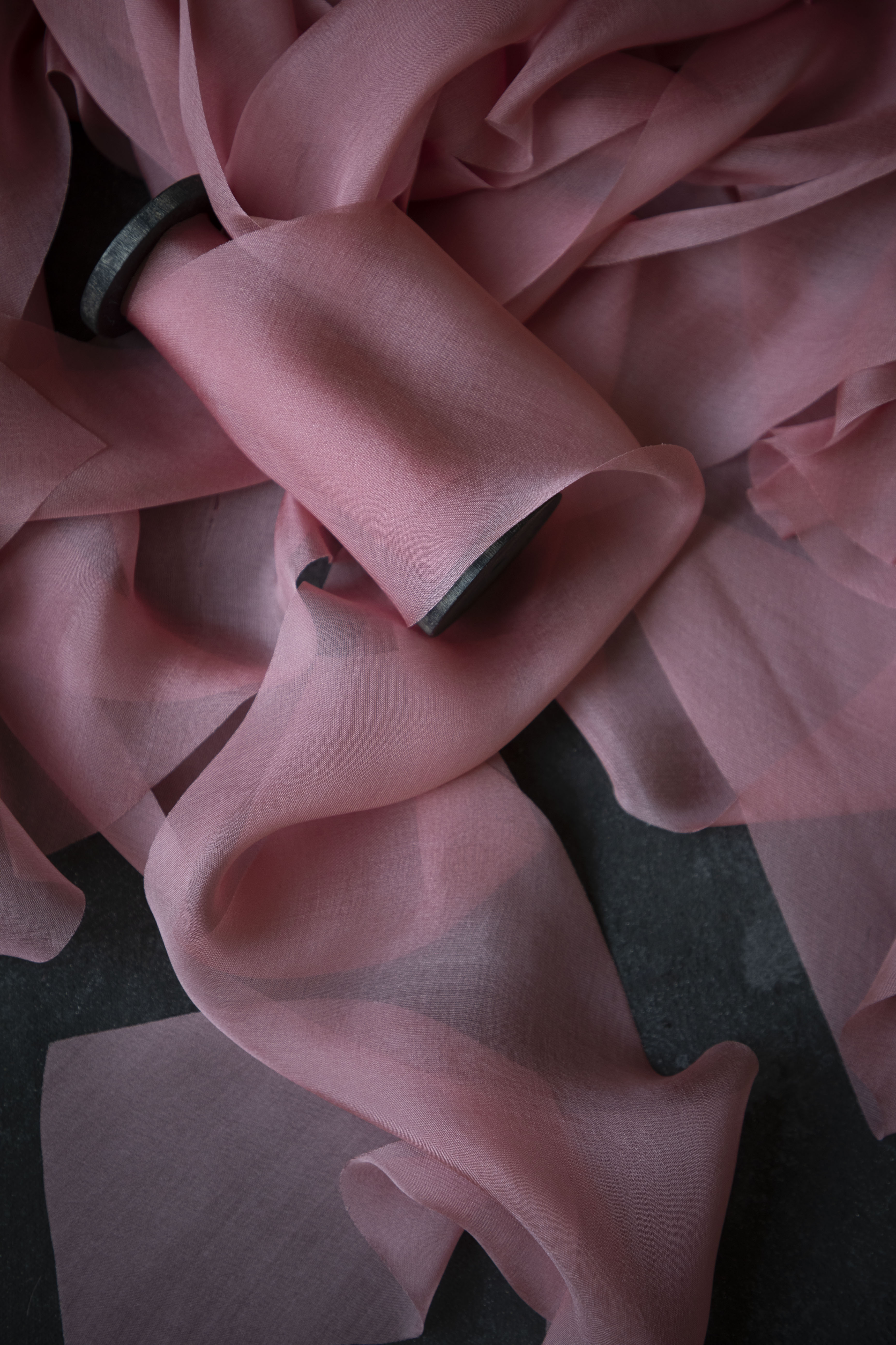 Close-up of a pink silk ribbon with a dark background