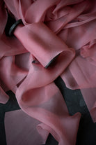Close-up of a pink silk ribbon with a dark background