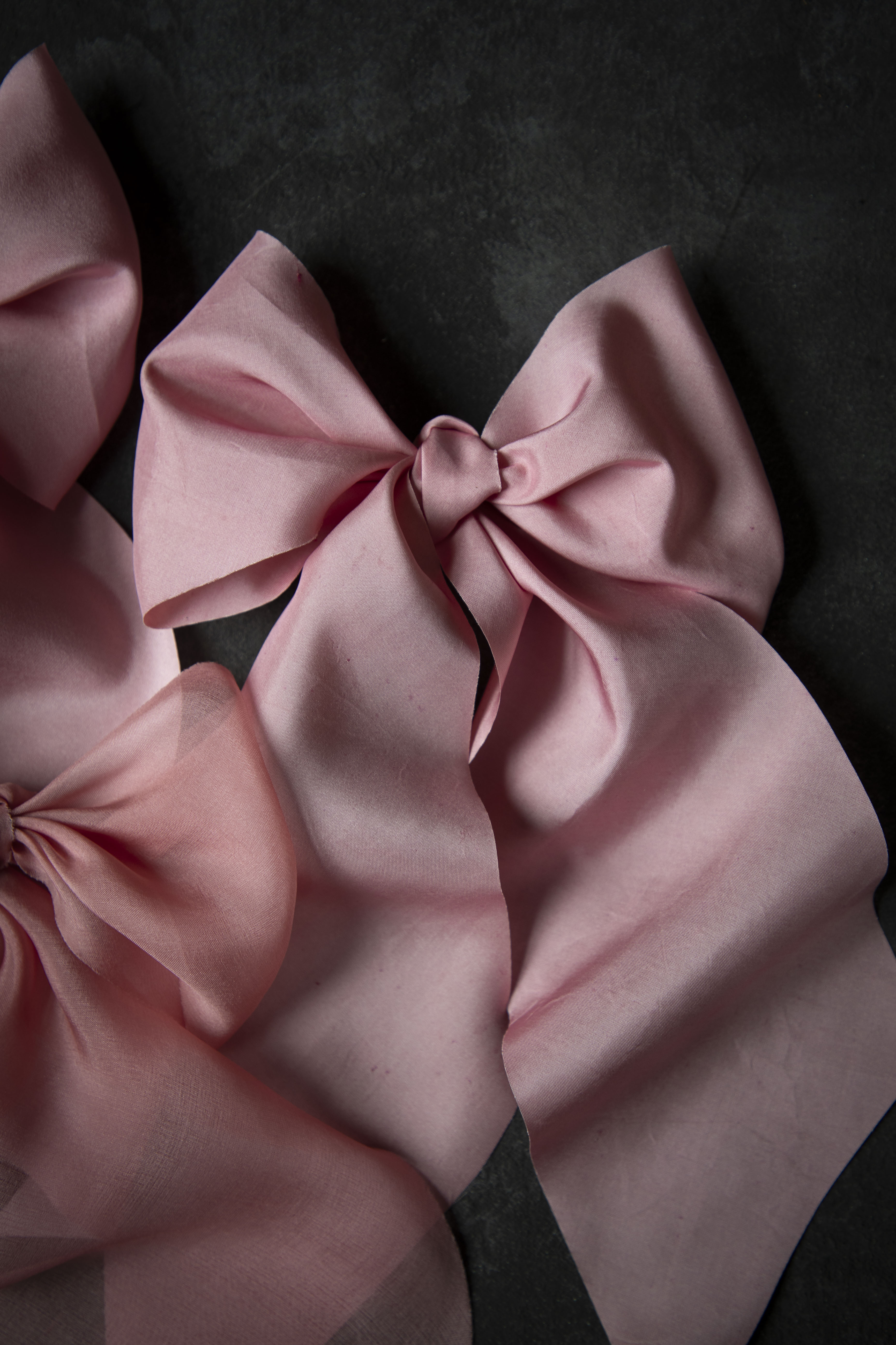 Pink satin hair bows on a dark background