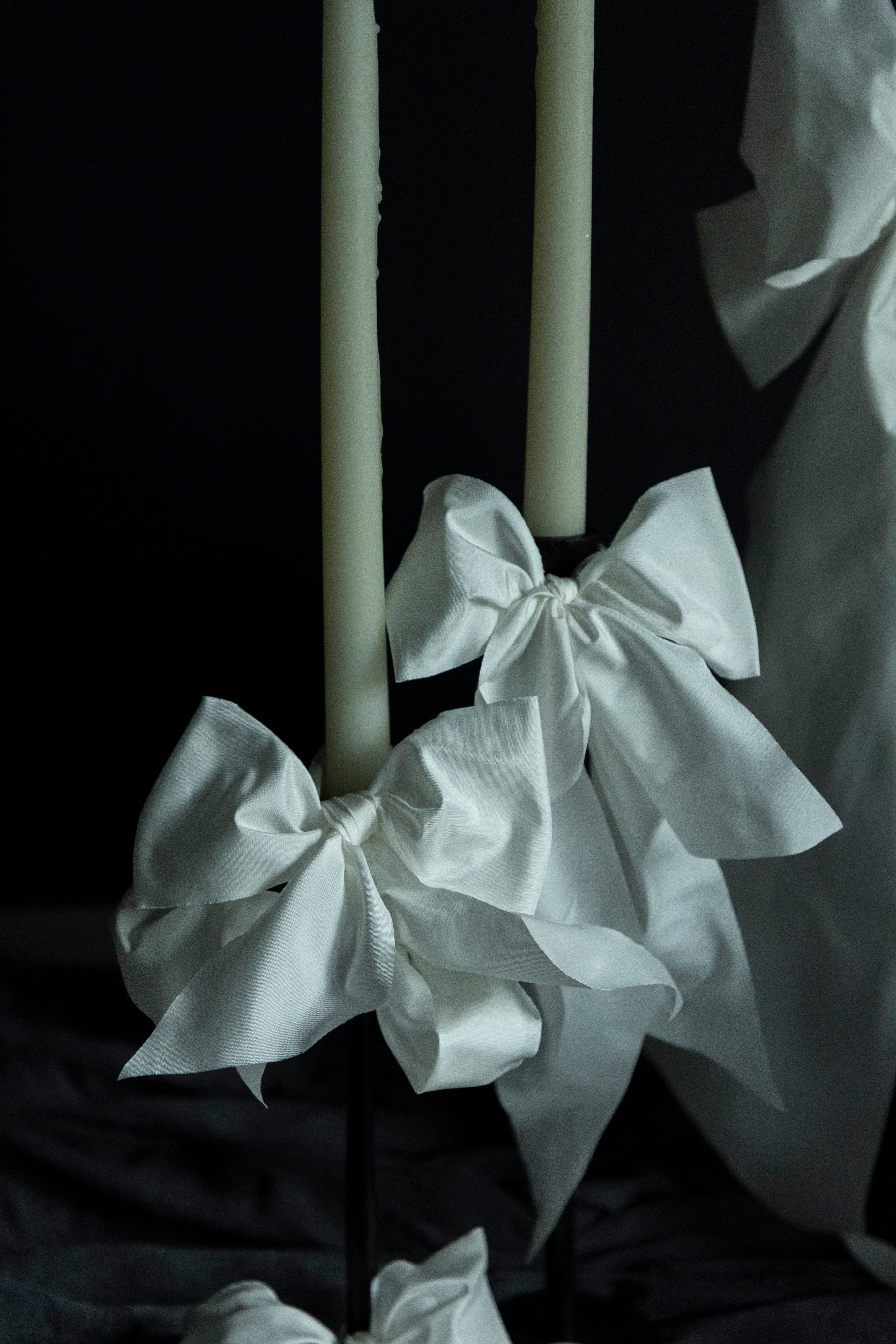 White ribbons tied around a candle against a dark background