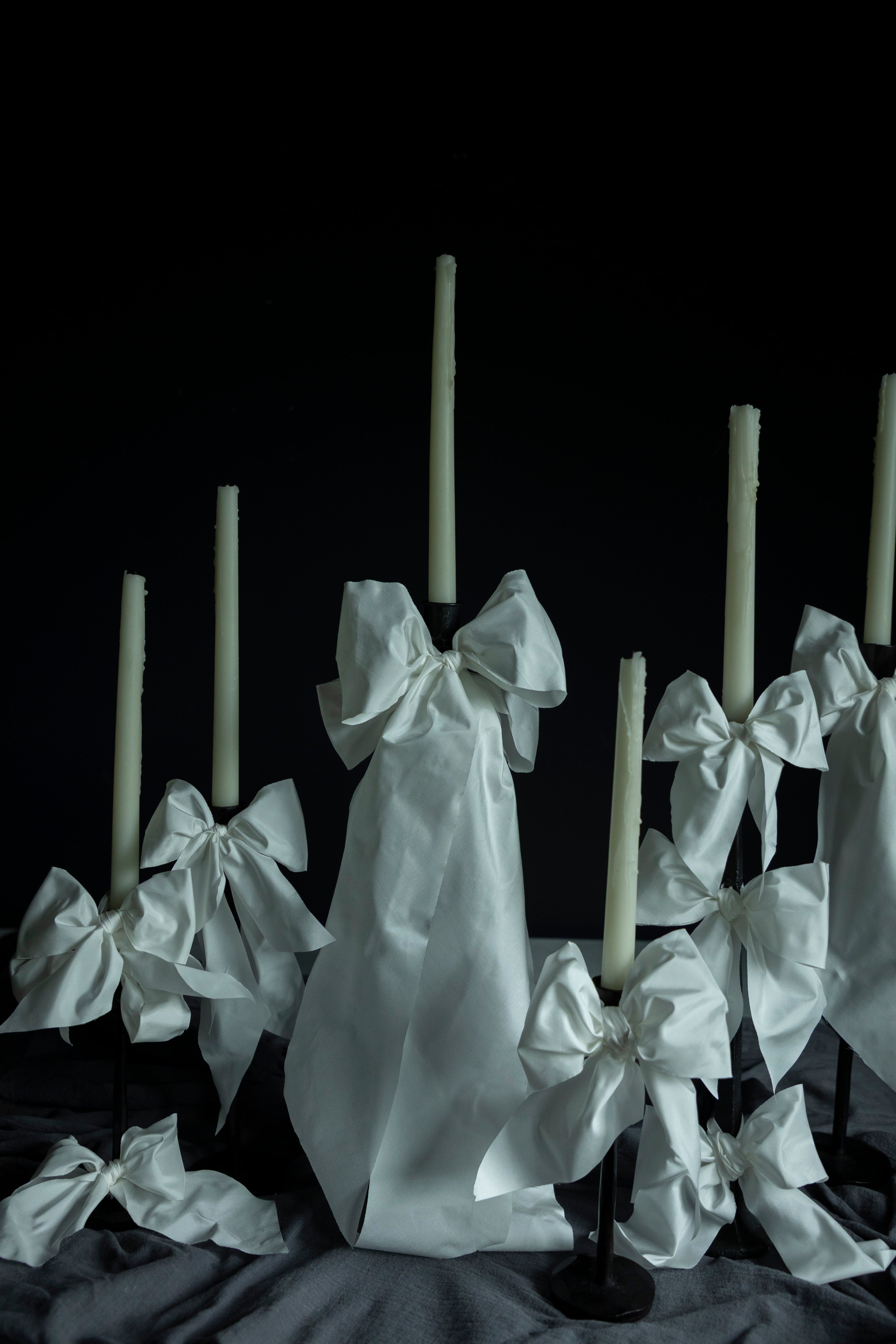 White candles with decorative bows on a dark background