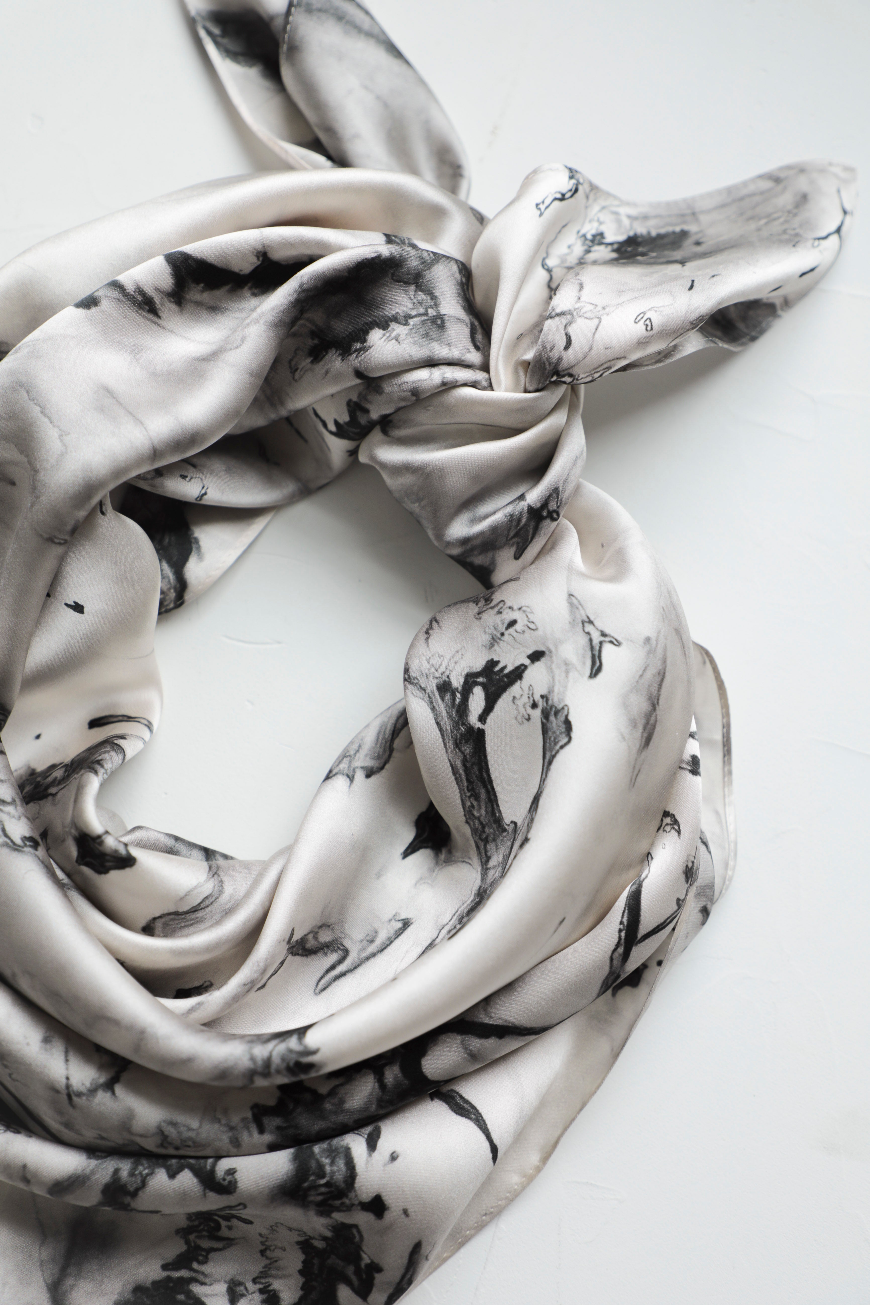 A silk satin scarf with a woodgrain-inspired black and white pattern, displayed on a white background.