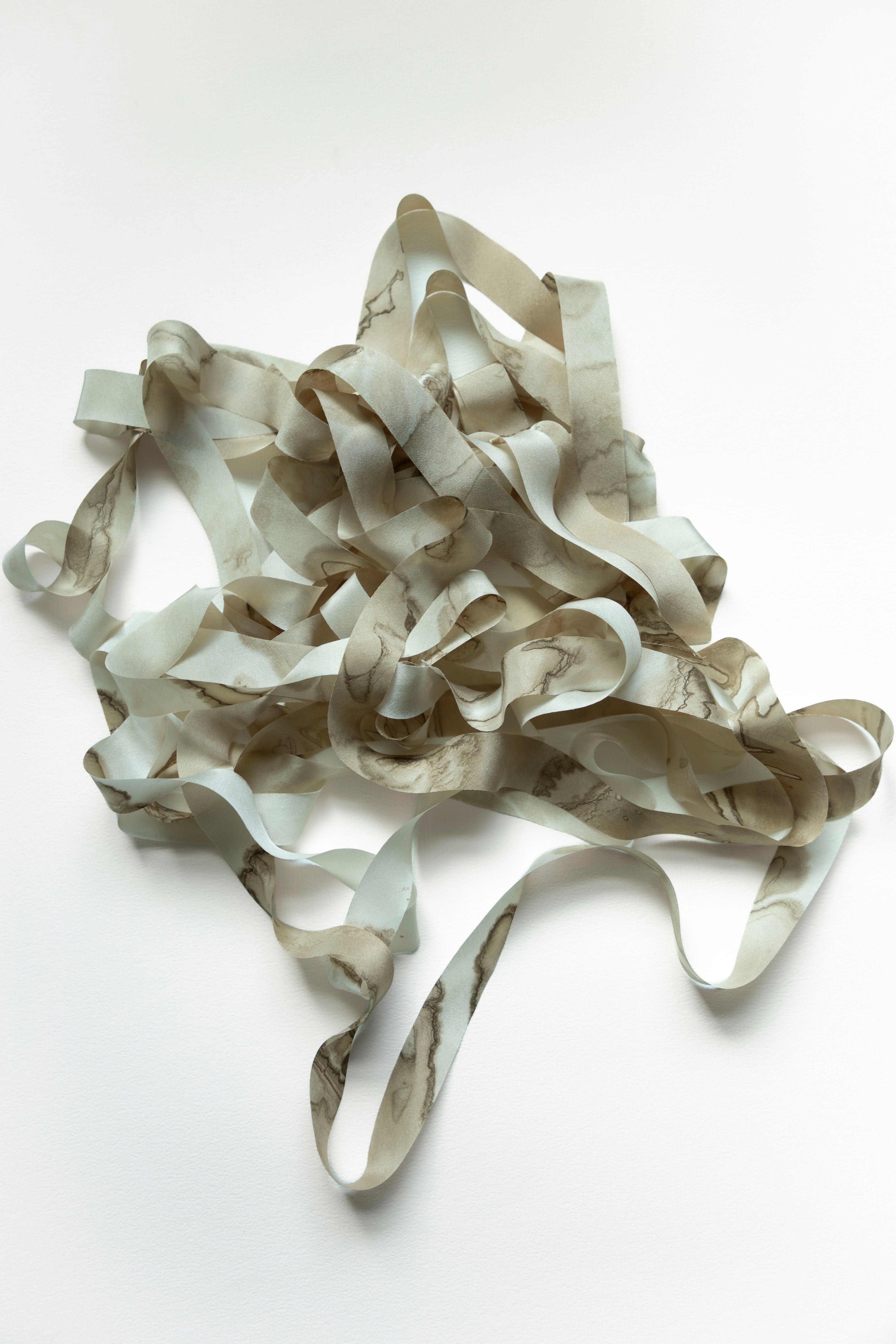 A pile of marbled silk ribbon, photographed on a plain white background.