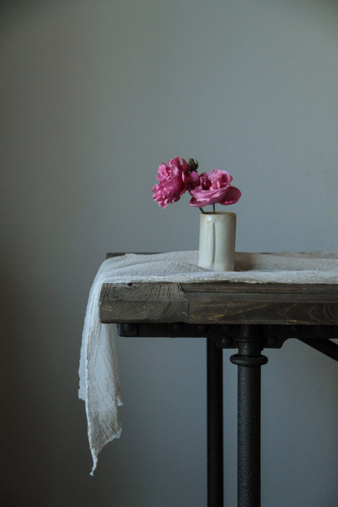 Silk and willow white table runner on a restoration hardware table and a vase with pink roses