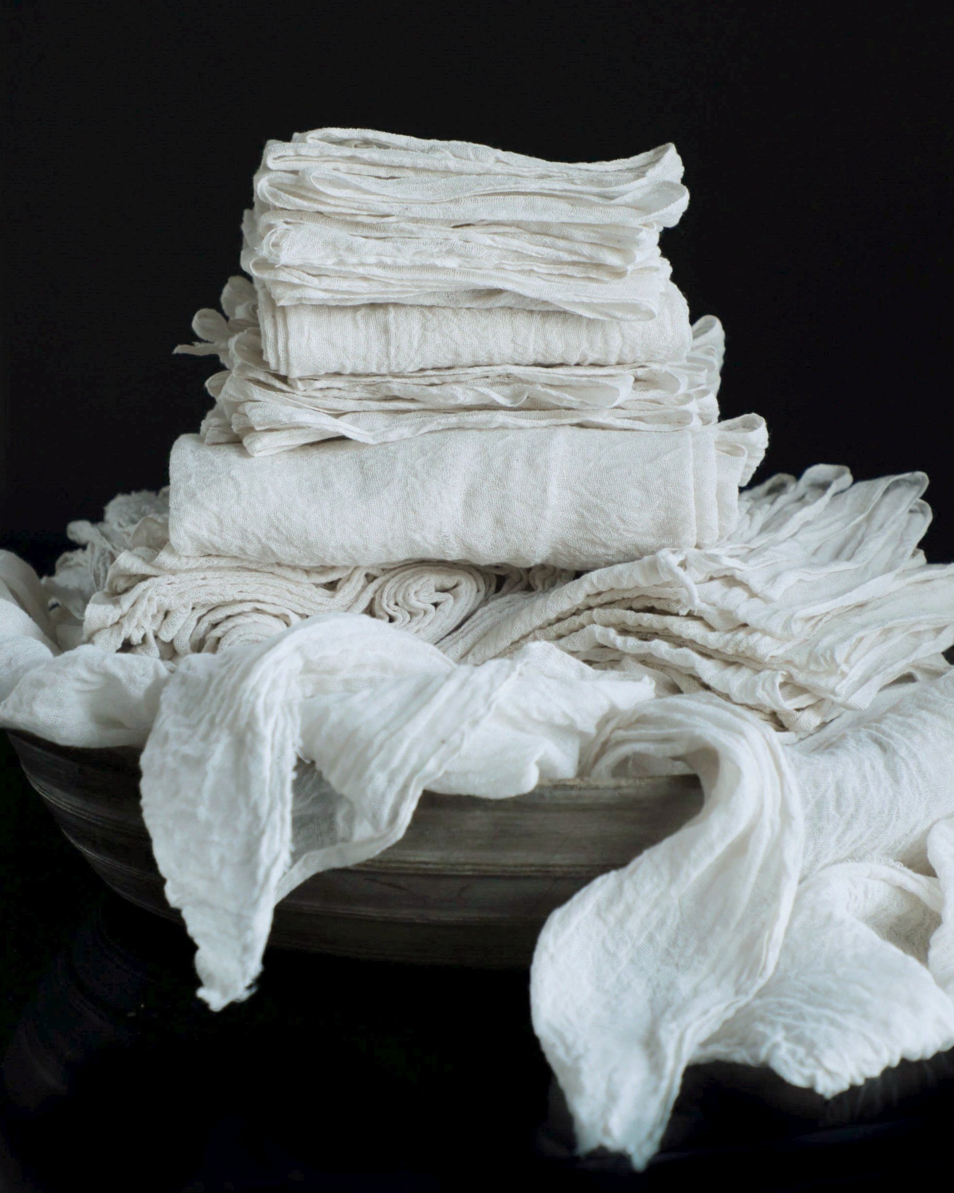 antique white cotton table runners stacked in a wooden bowl