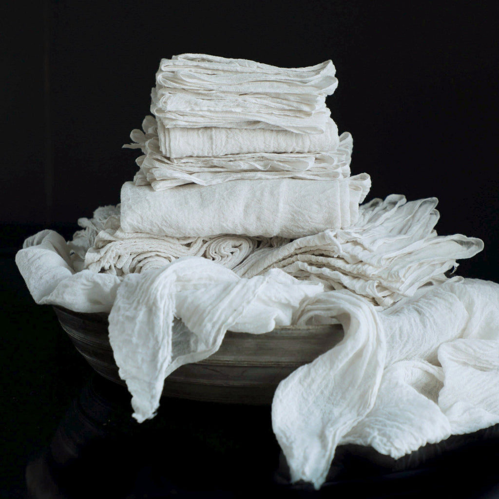 antique white cotton table runners stacked in a wooden bowl