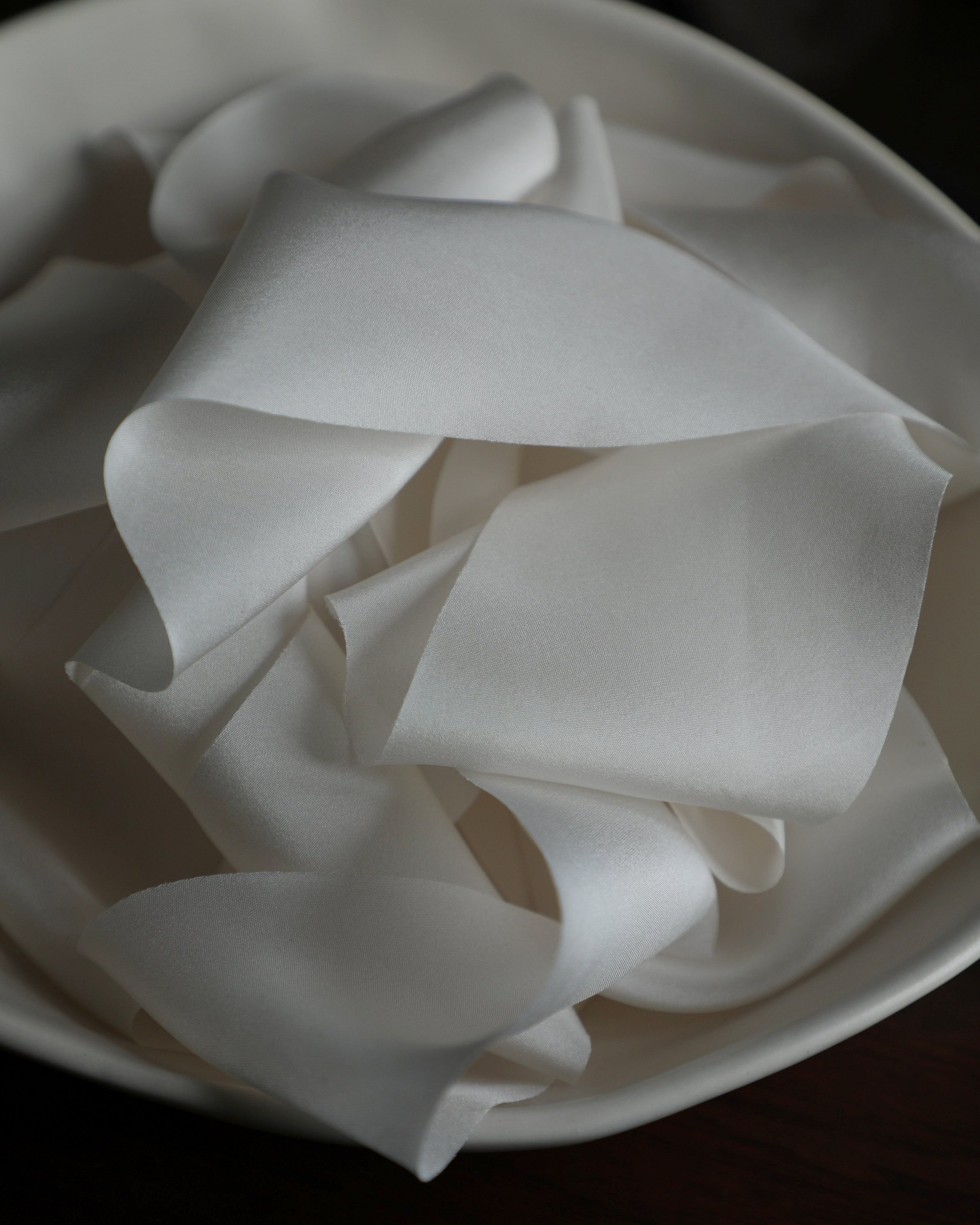 antique white silk ribbon displayed in a ceramic bowl
