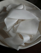 antique white silk ribbon displayed in a ceramic bowl