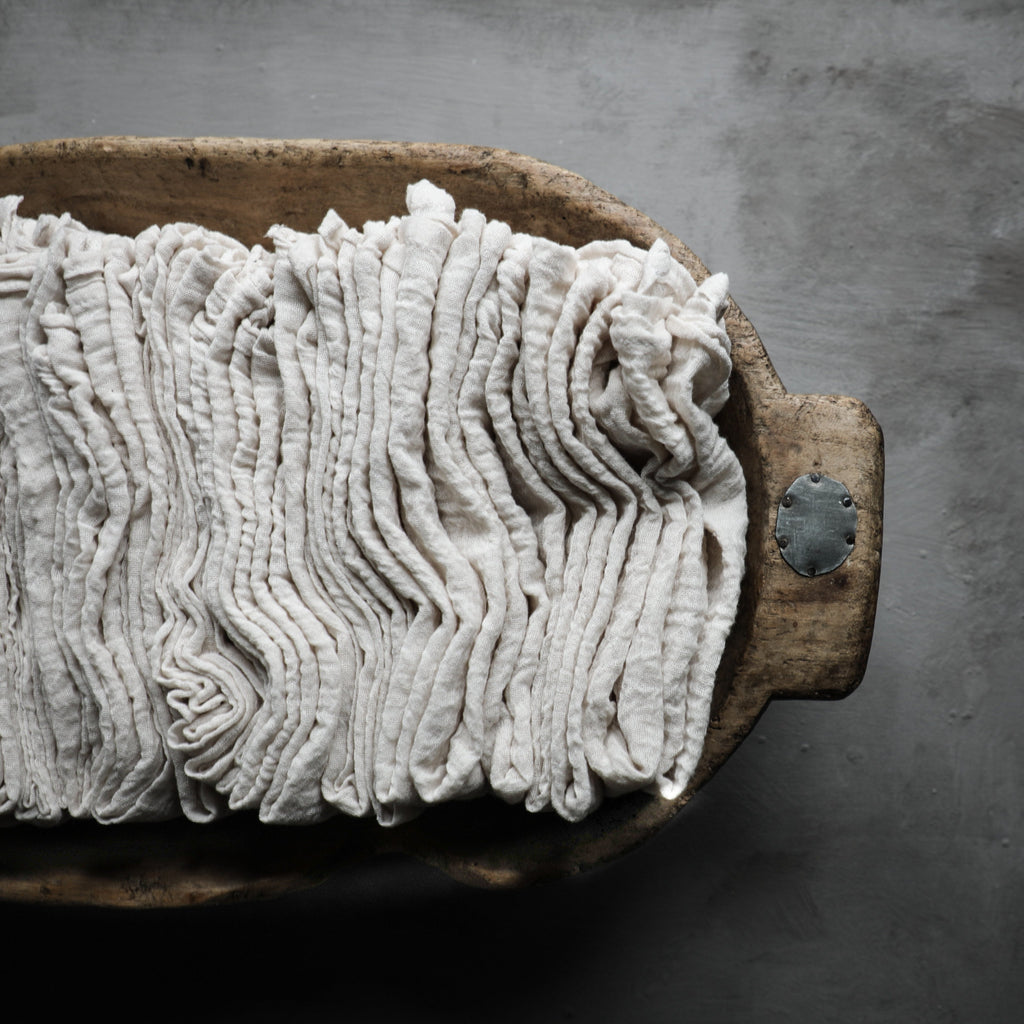 Antique white napkins displayed in a vintage bread bowl