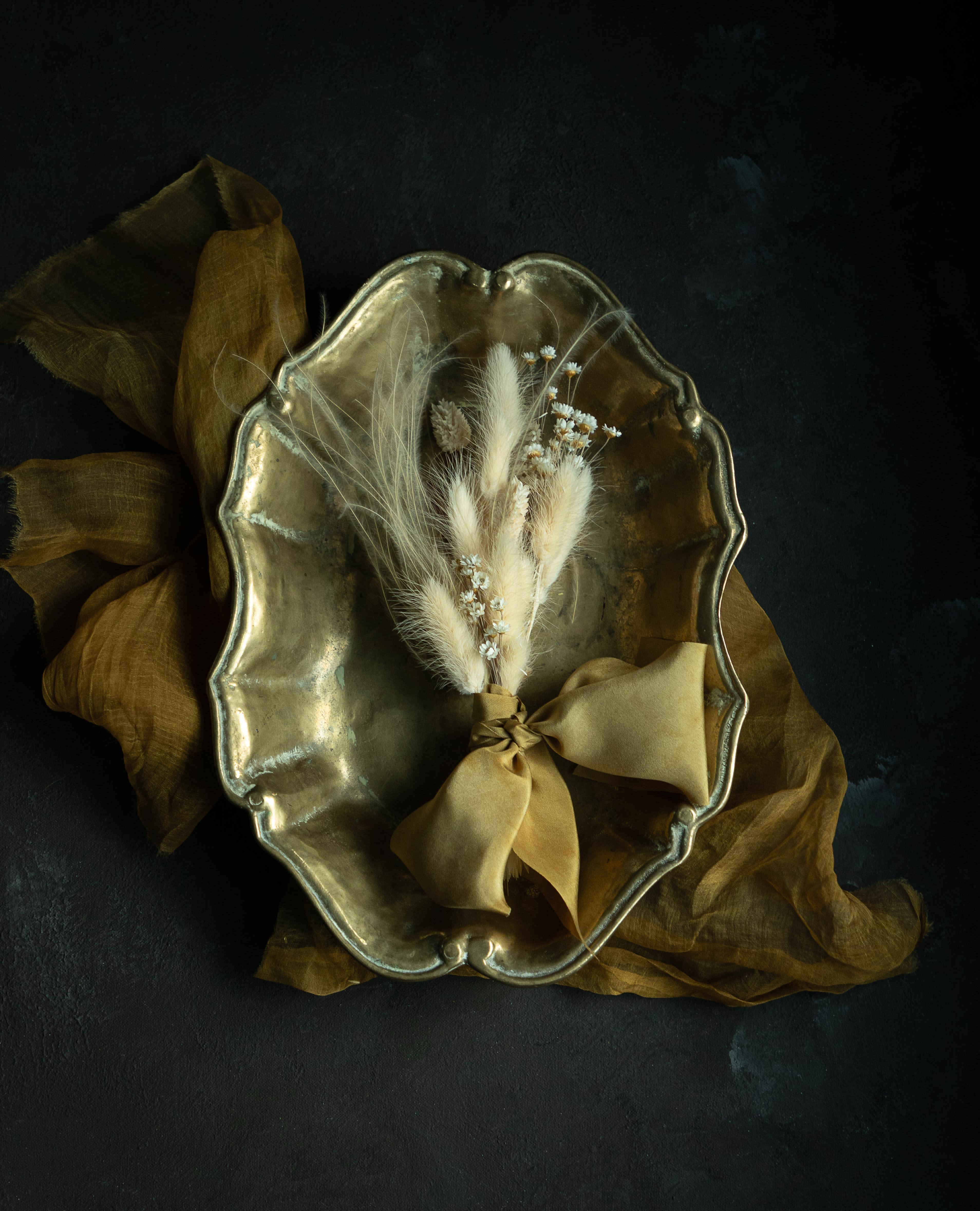 Plant-dyed silk ribbon displayed elegantly against a textured background, showcasing its luxurious sheen and soft hues, ideal for wrapping bridal bouquets. Perfect for brides-to-be, engaged couples, and florists seeking the world's finest ribbon for wedding flowers.