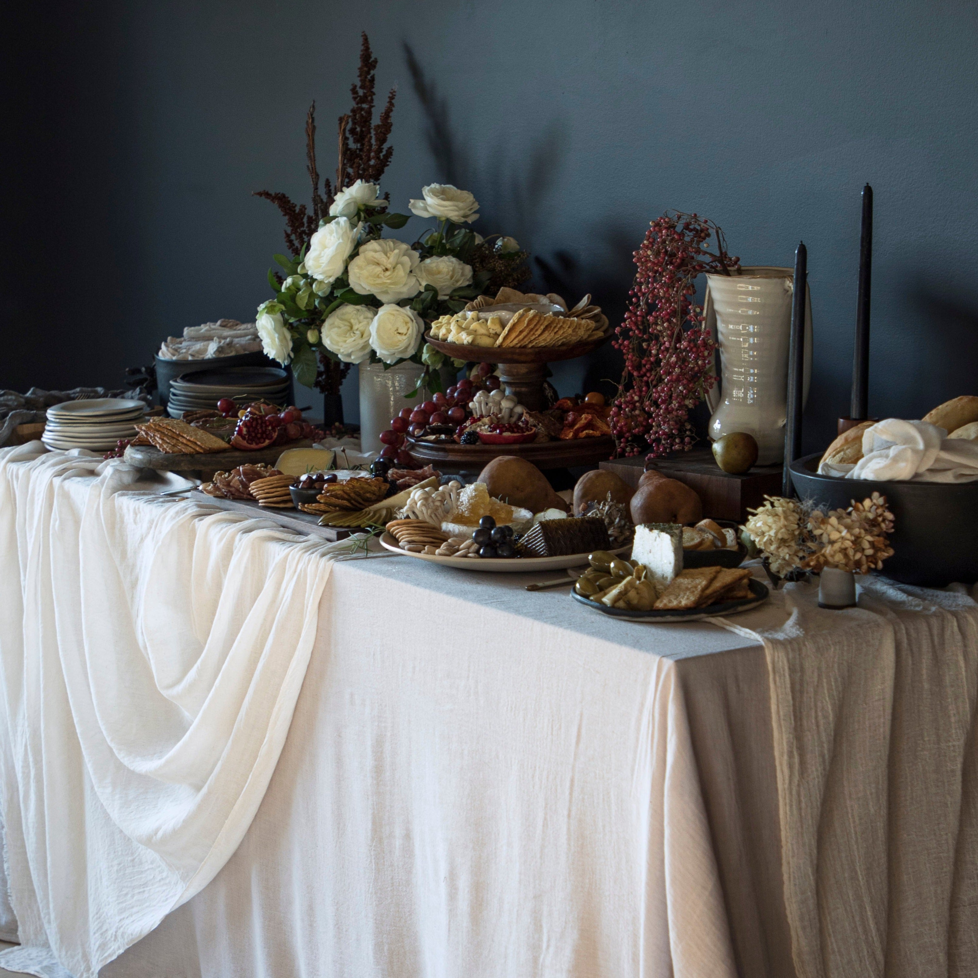 Antique white hand-loomed plant-dyed cotton table runner draped elegantly across a grazing table design, showcasing its unique textures and natural hues, ideal for creating a bespoke tablescape design.