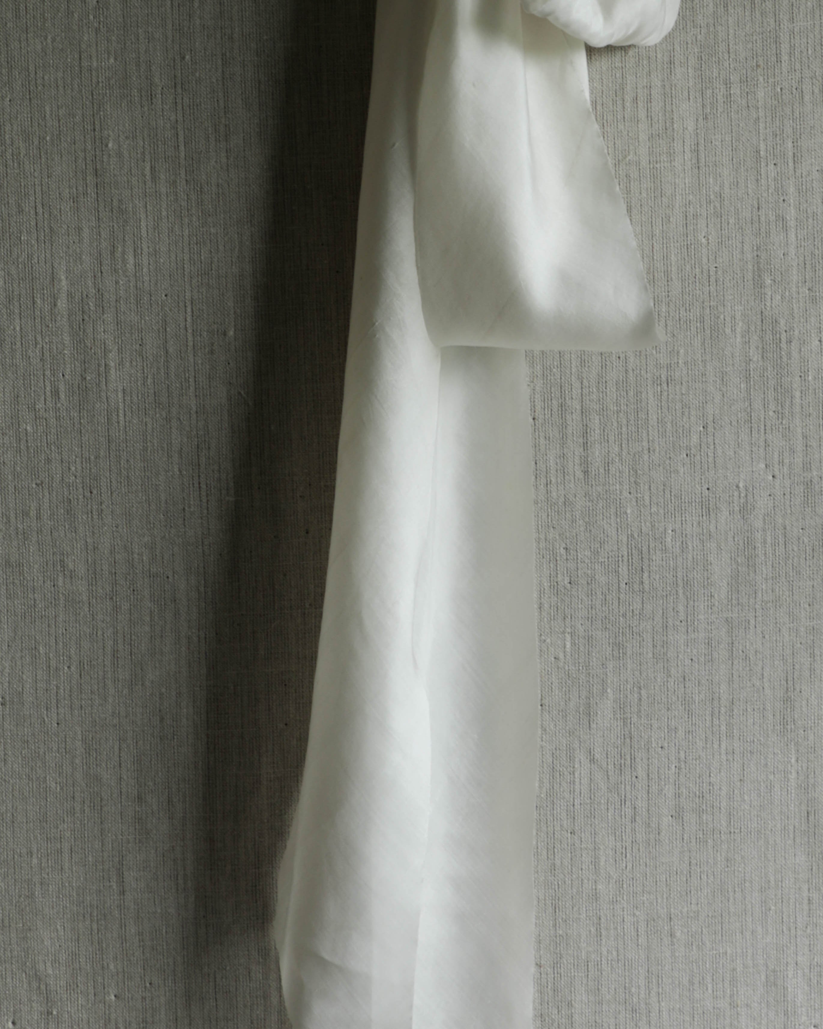 antique white silk ribbon on a linen pin board 